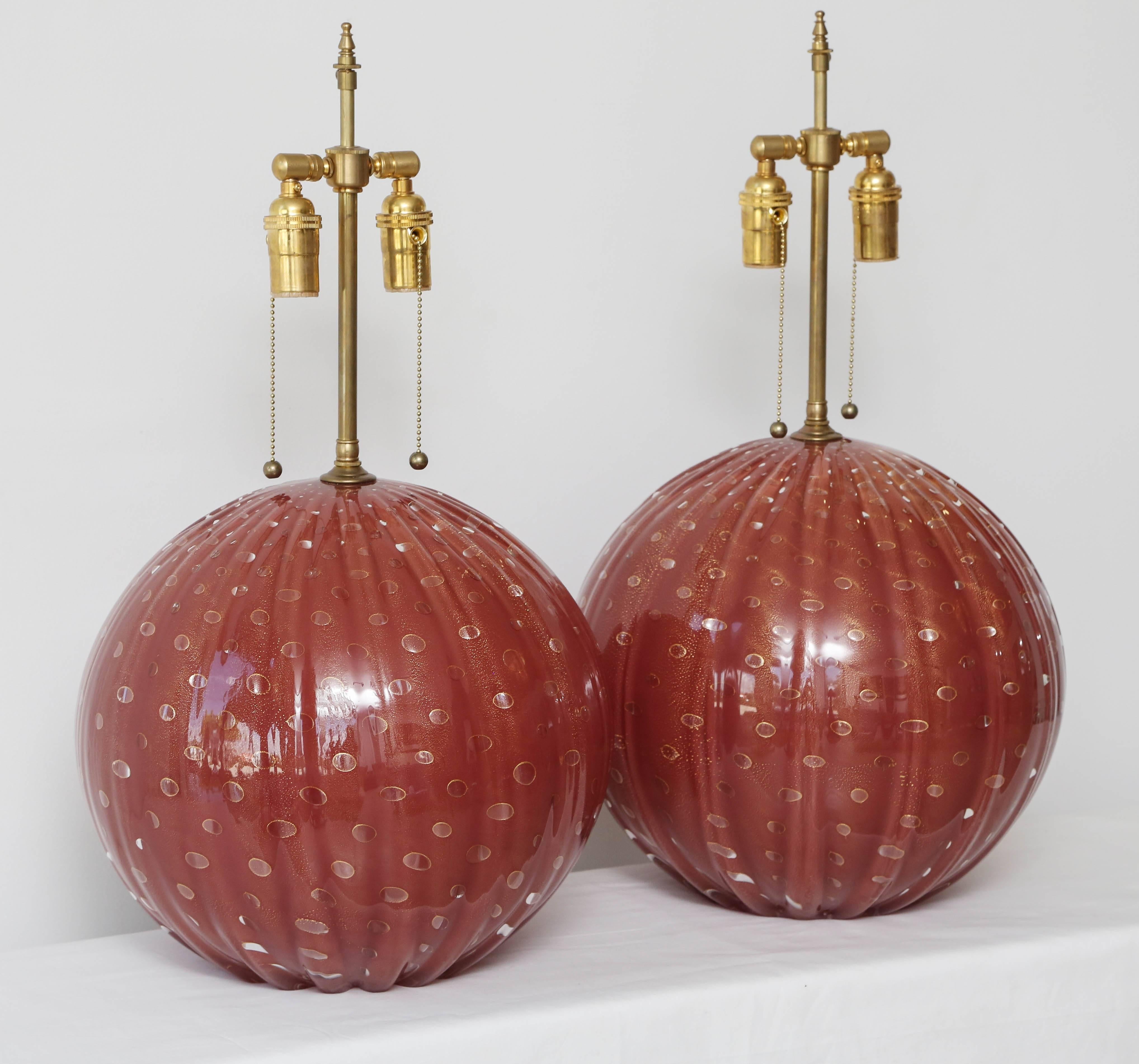 Pair of deep red fluted Murano glass lamps with controlled internal gold bubbles.