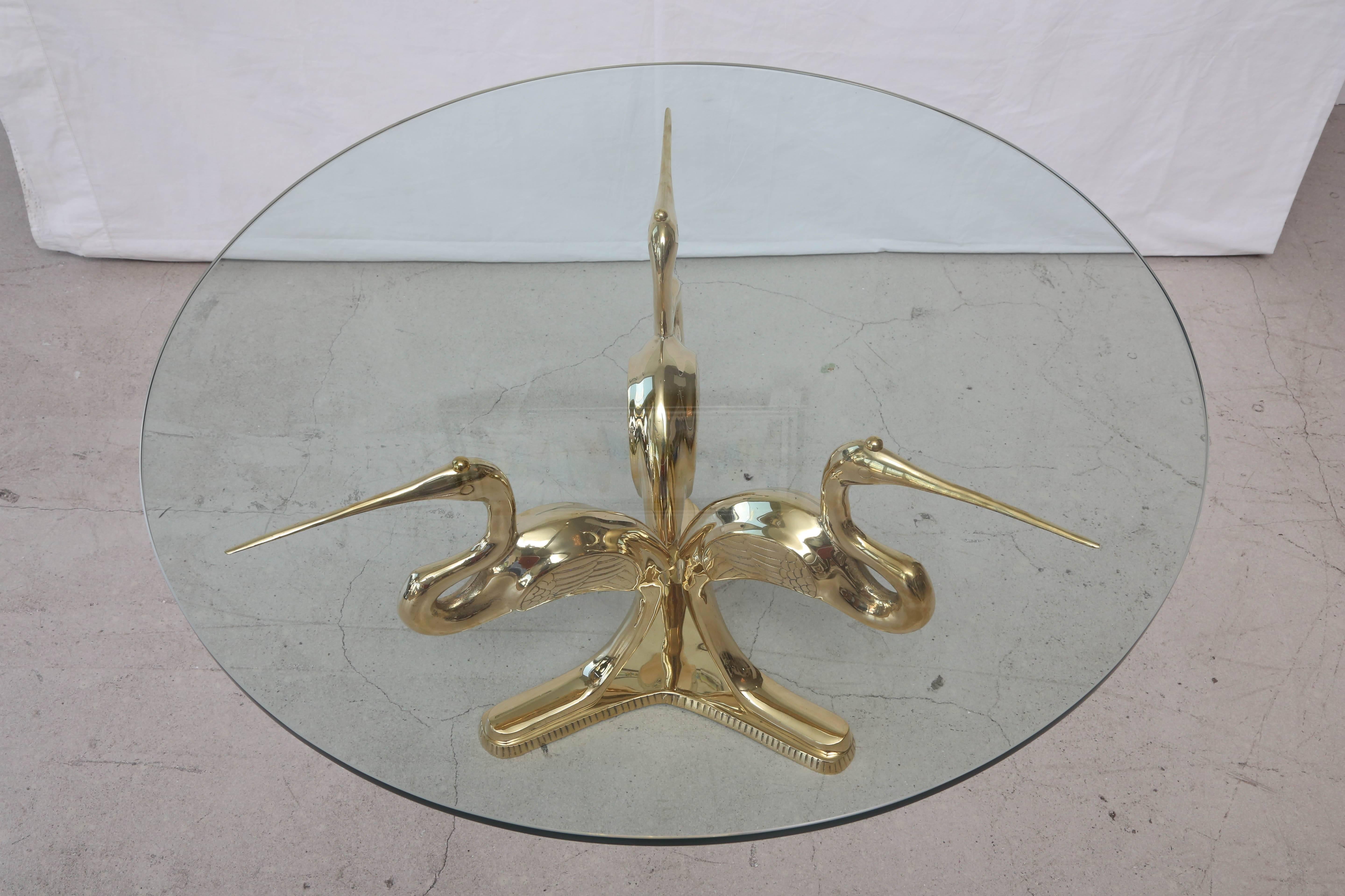 Vintage Italian polished brass table with three herons with a circular glass top.
  