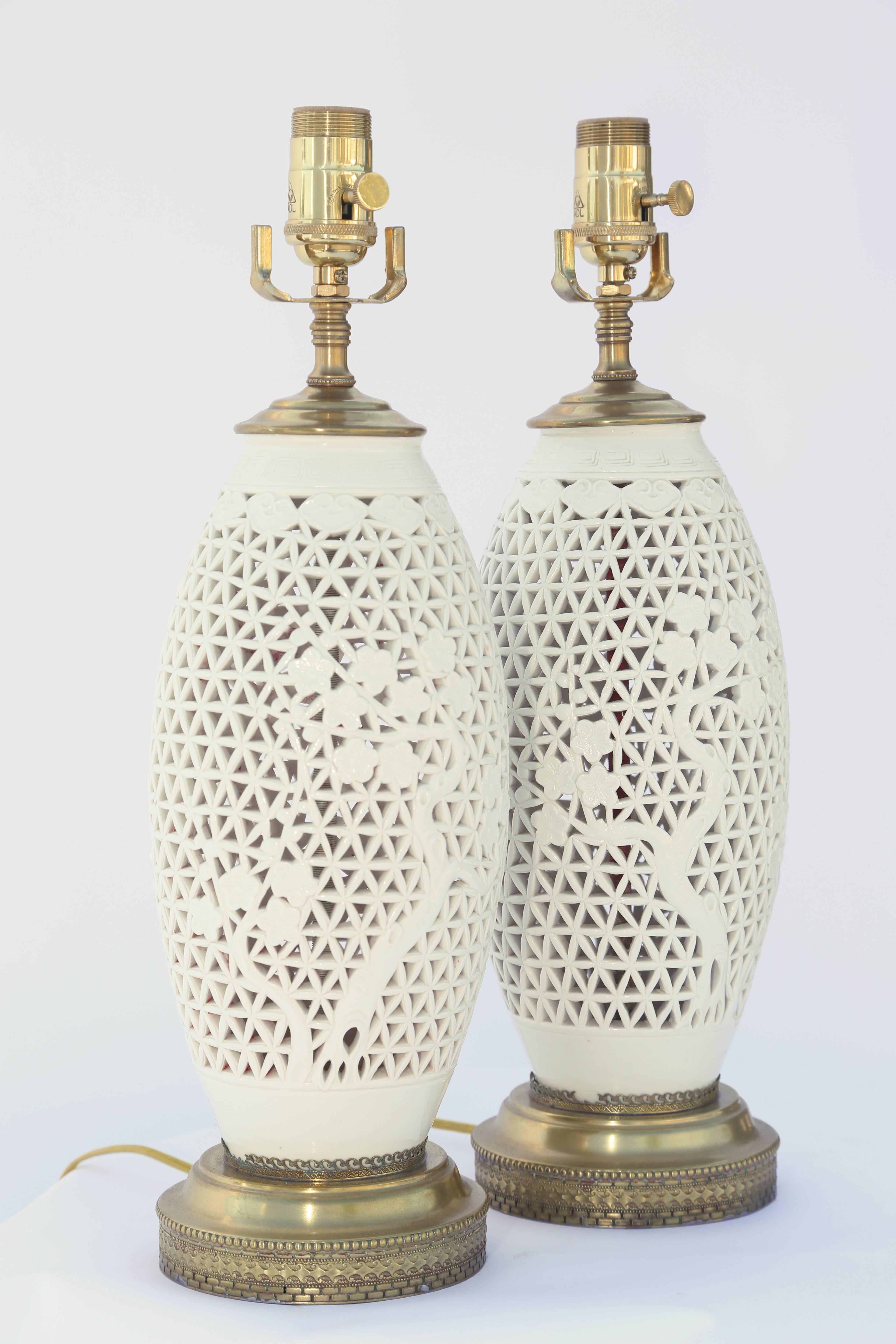 Pair of lamps, each a blanc de chine piercework porcelain vase, its ovoid body decorated with blooming trees, lamped on brass bases.

Stock ID: D9433