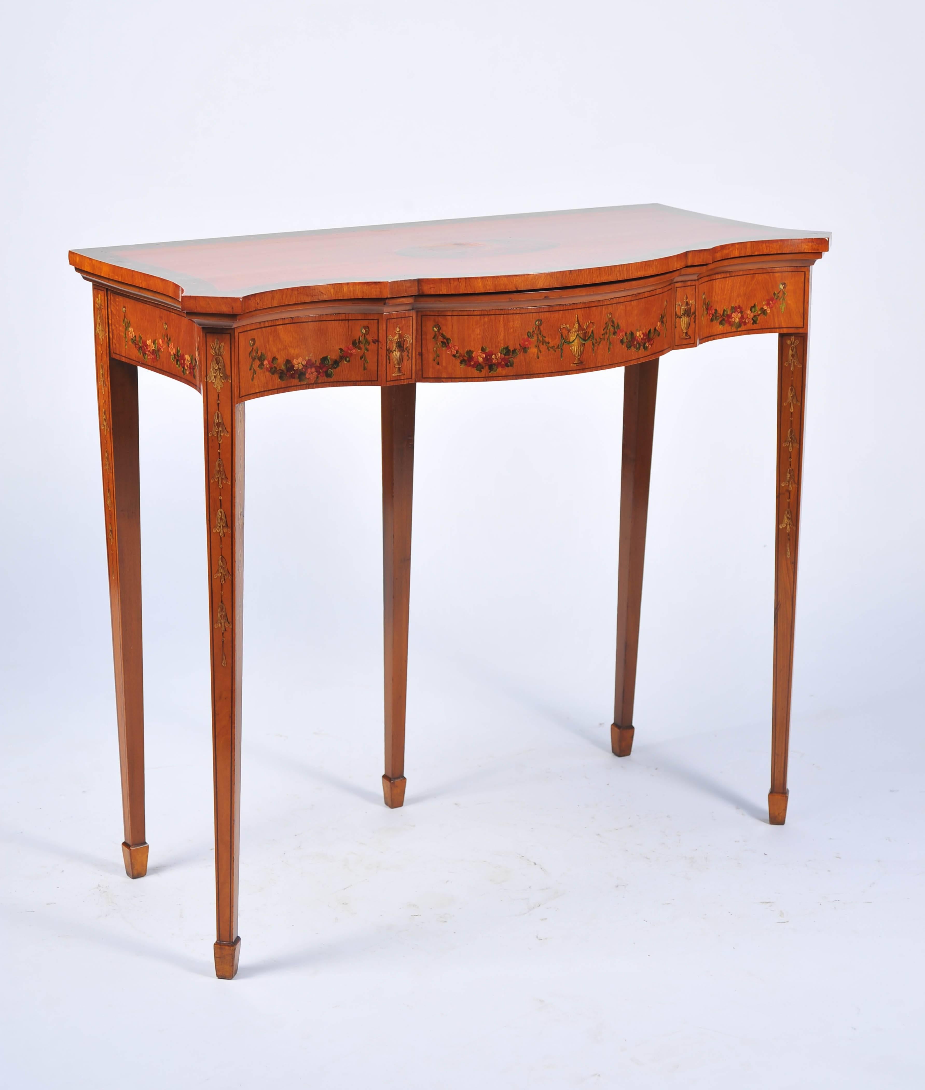 A good quality late 19th century Sheraton Revival Satinwood card table, having classical hand-painted decoration of flowers and urns. The top opening to reveal a baize lined card playing surface. Raised on square tapering legs, terminating in spade