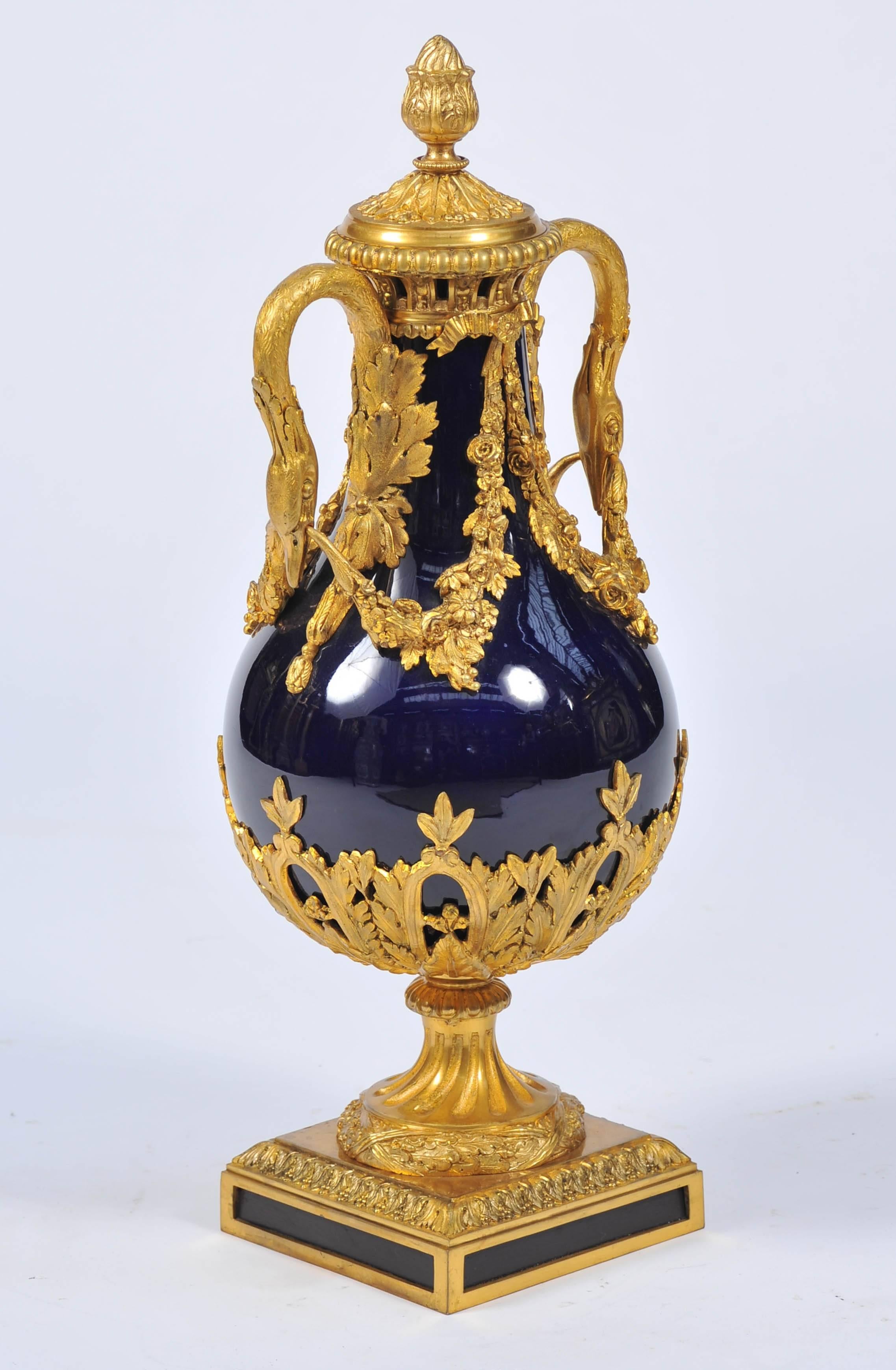 A good quality late 19th century gilded ormolu Louis XVI style vase, with a Royal blue Paris porcelain vase. Having classical swan like handles, foliate swags, leaf decoration to the base and raised on a twisted fluted sockle and square with blue