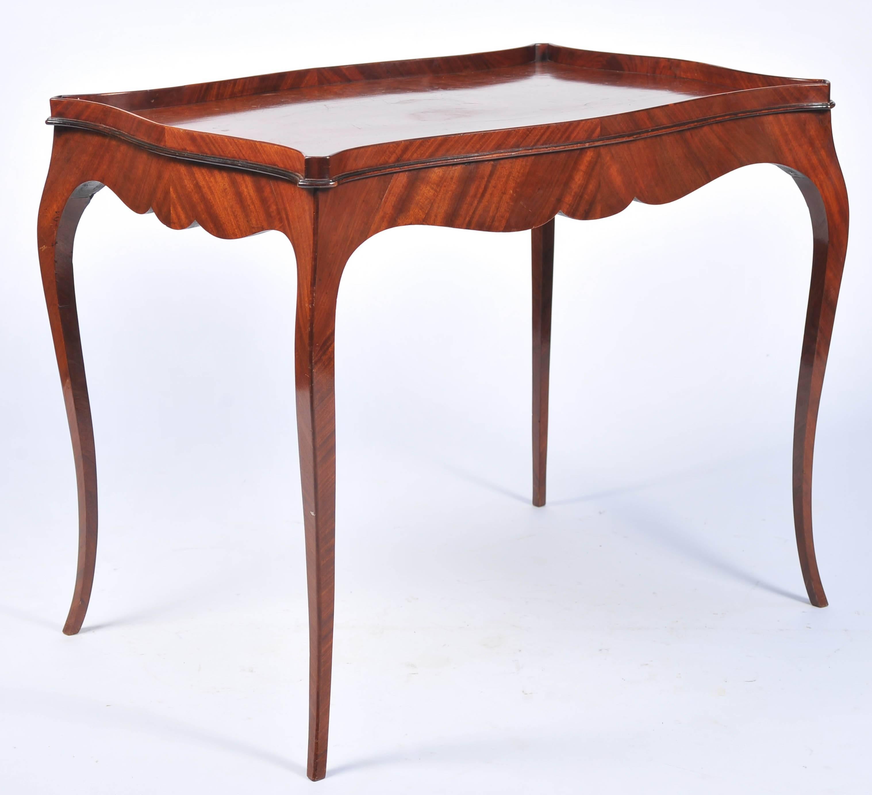 A very elegant 18th century mahogany French Hepplewhite silver table, having a serpentine form, gallery to the top, a shaped apron, and raised on cabriole legs.