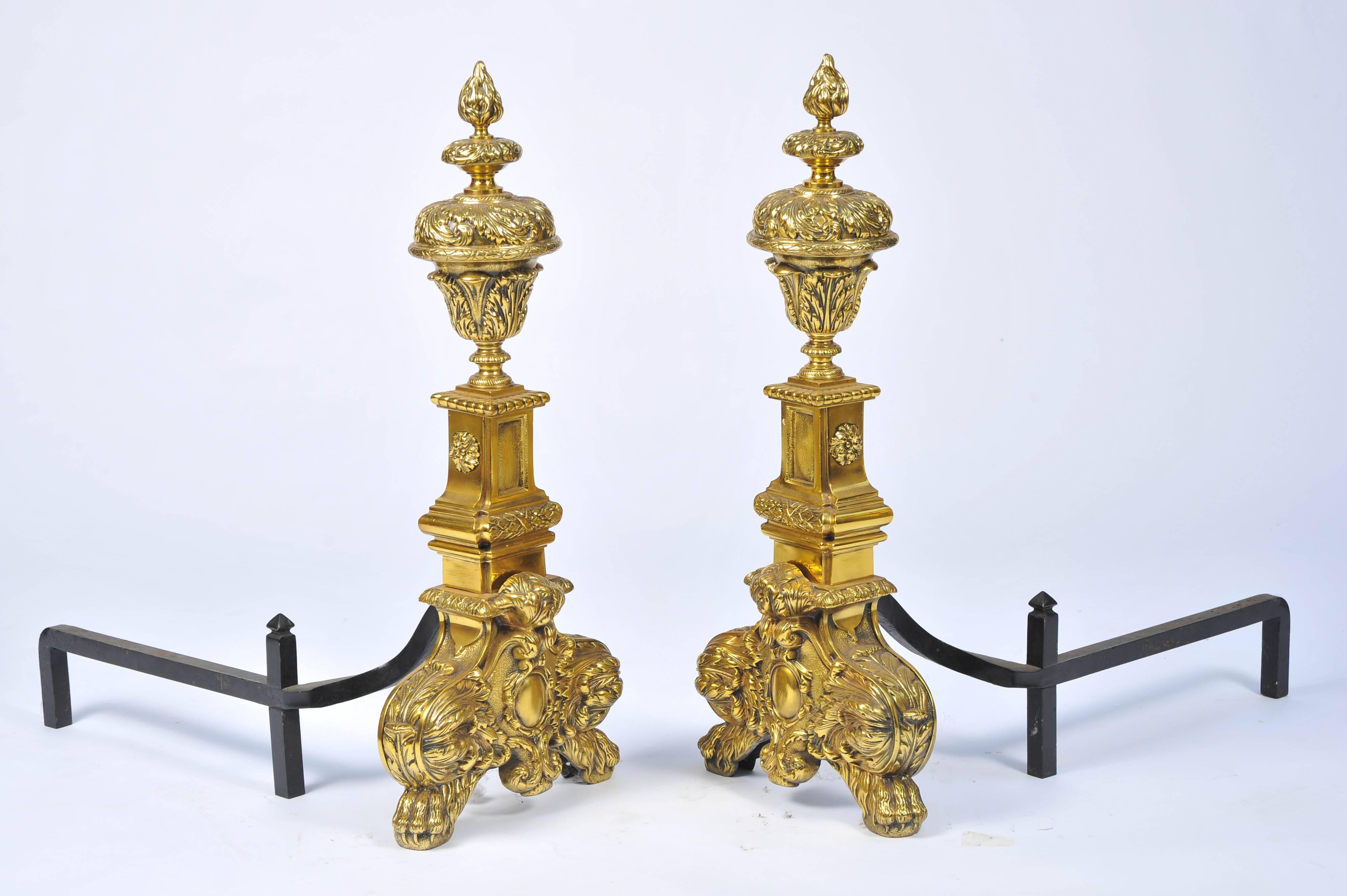 A very impressive pair on 19th century classical brass fire dogs. Having flame like urn finials set on a plinth, raised on foliage decoration and claw feet.