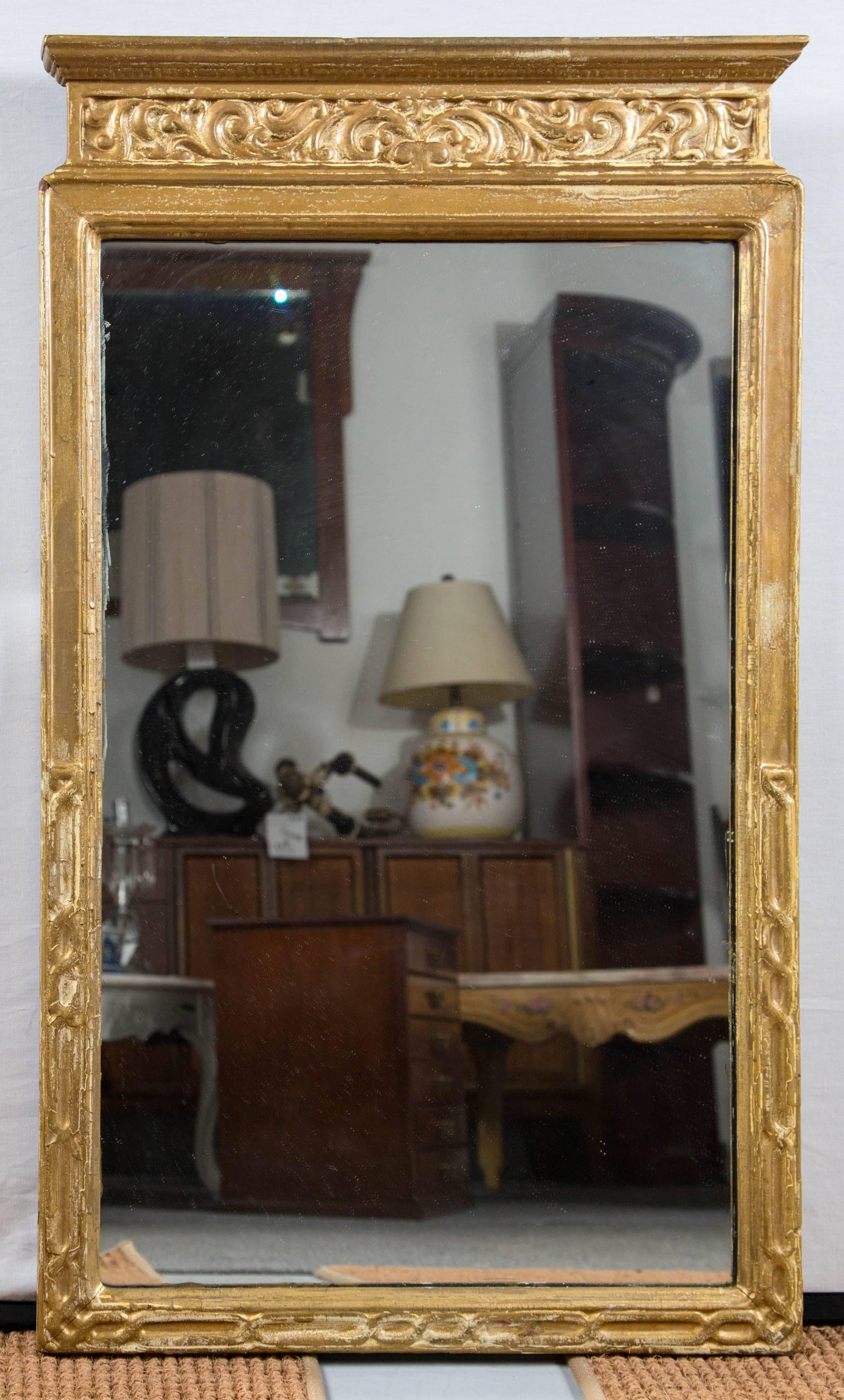 Neoclassic giltwood frame mirror, circa 1920s. Lovely pediment shape frame with carved detail across top and sides. Aged gilt surface. 