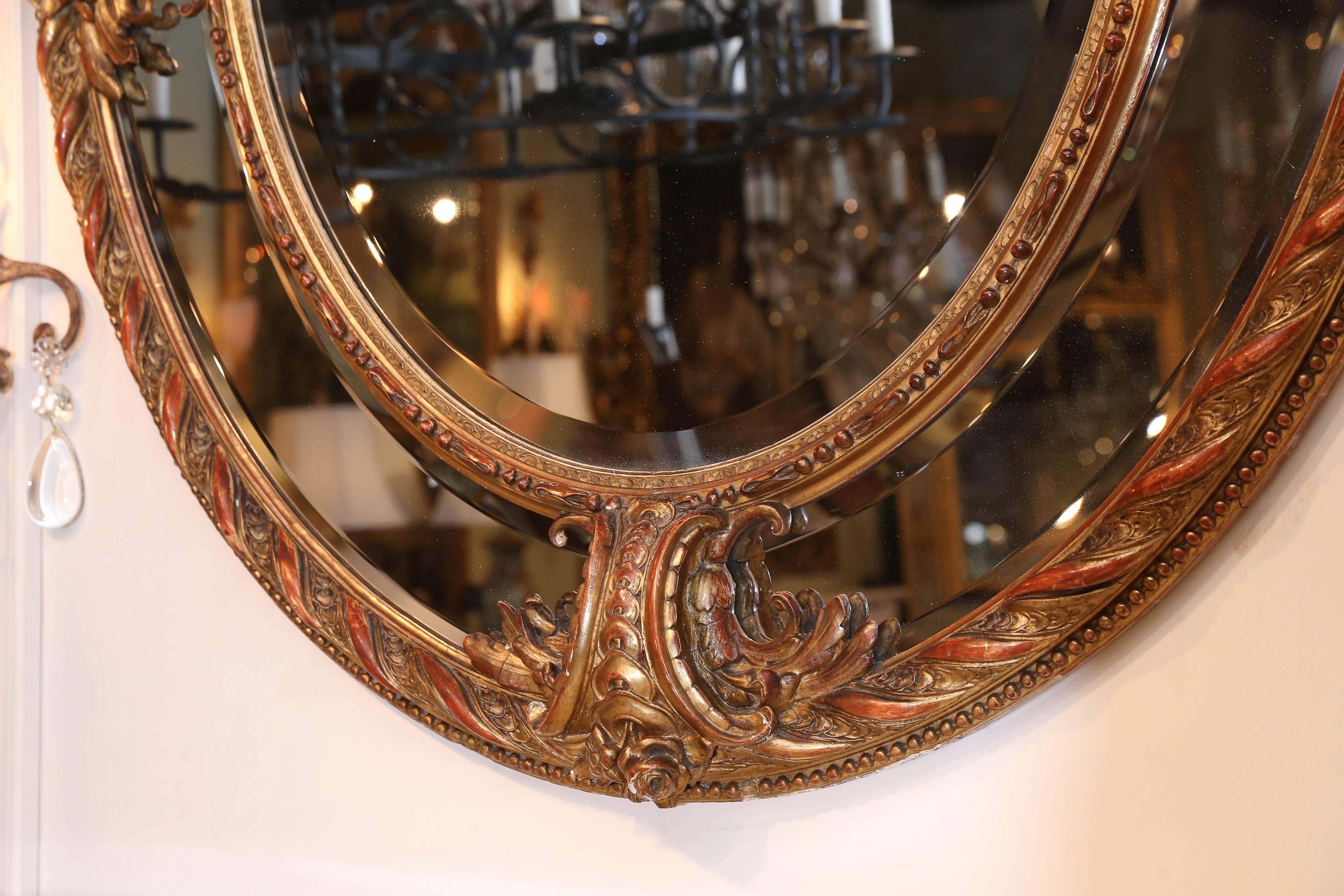 19th century French oval gilt mirror having a beveled central plate within border
Surrounded by stepped beveled plate In the Louis XVI style;
Having an elaborate ribbon and floral crest.