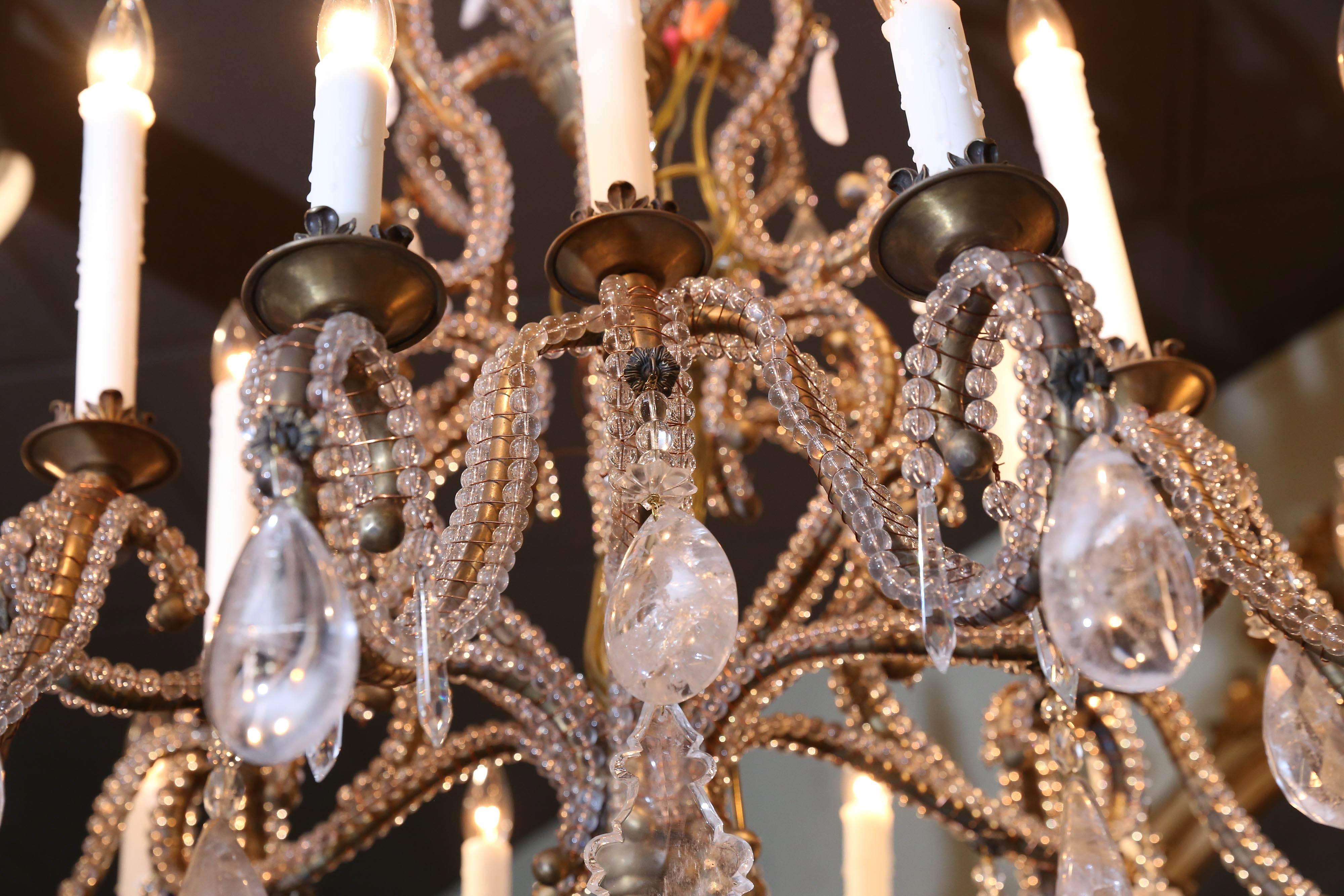 Italian style beaded chandelier with small beads that decorate the
Scrolling arms of this piece. It has fifteen lights. It is adorned with rock
Crystal in several sizes, and has a large oval piece of rock crystal in a finial
shape at the bottom