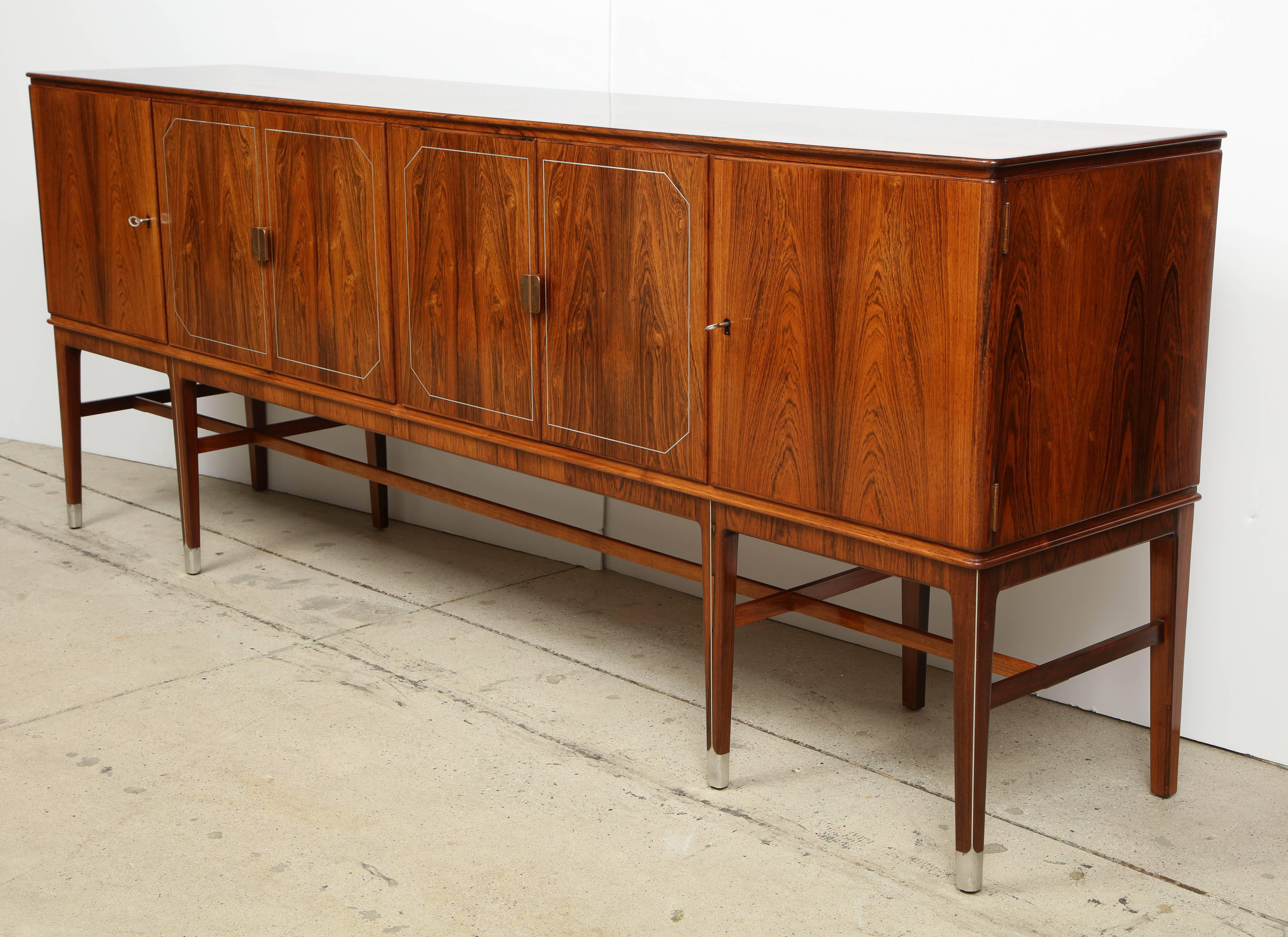 A superb Danish sideboard in Brazilian rosewood with white metal inlays (probably pewter) designed by Agner Christoffersen and produced by N.C Christoffersen, circa 1950s, six cabinet doors with patinated copper pulls opening to a fitted interior