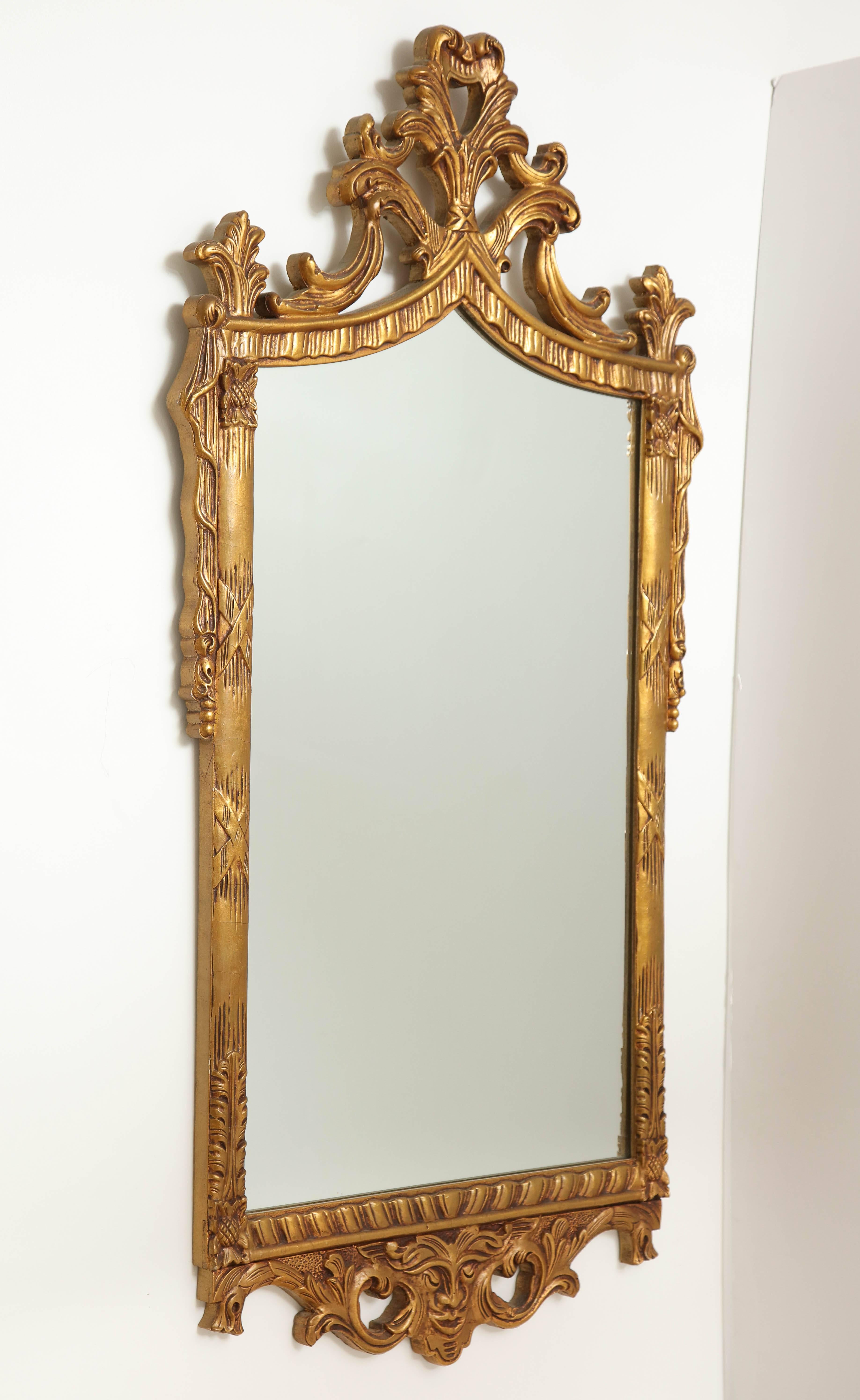 Extravagantly carved and gilded wood framed mirror featuring draped swags and acanthus details.