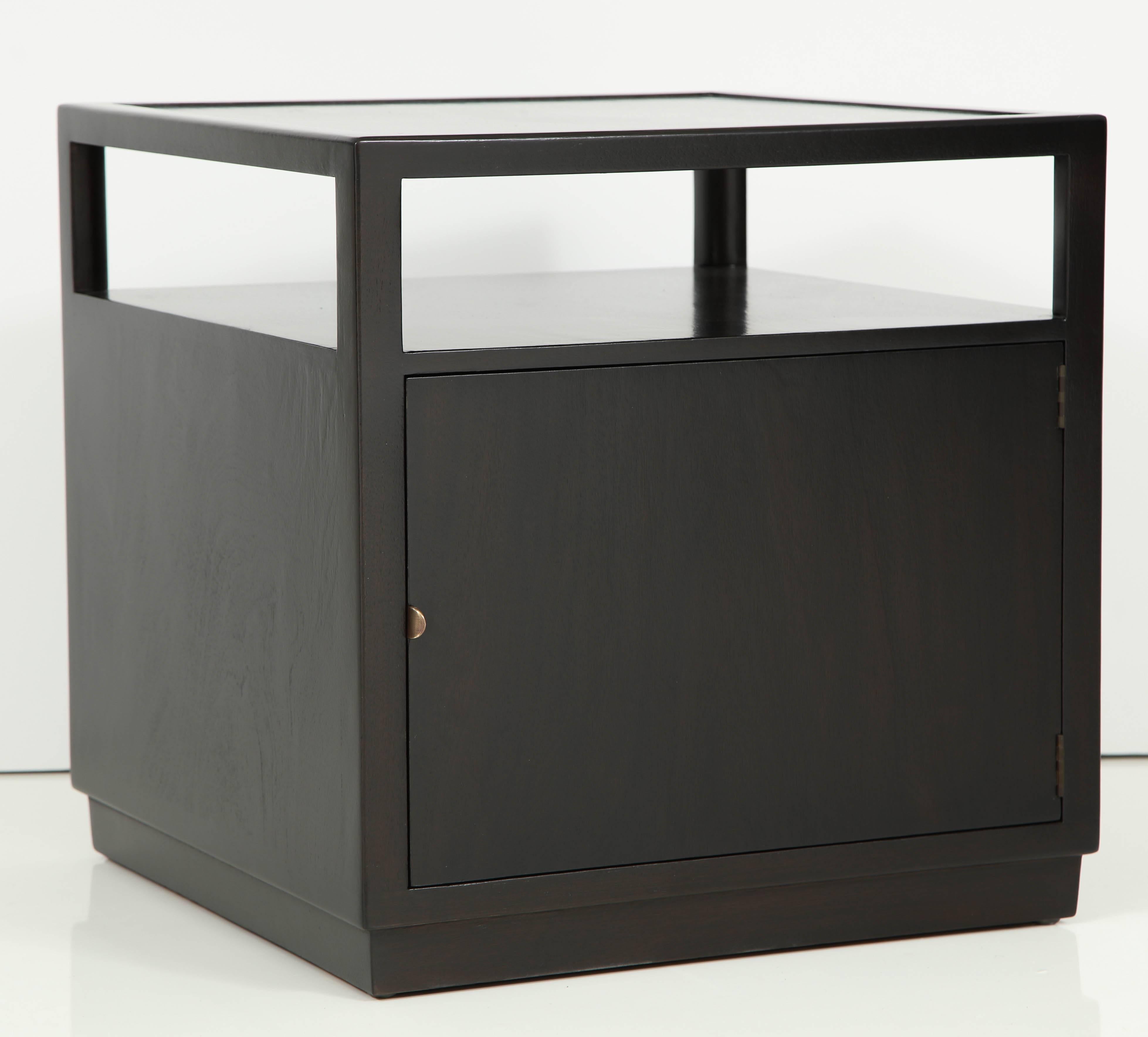 Mid-Century classic cube form ebonized Mahogany side tables/ nightstands with a bottom compartment and elevated top. Pieces have been restored in a dark ebony stain with a semi-gloss finish. Dunbar plate.