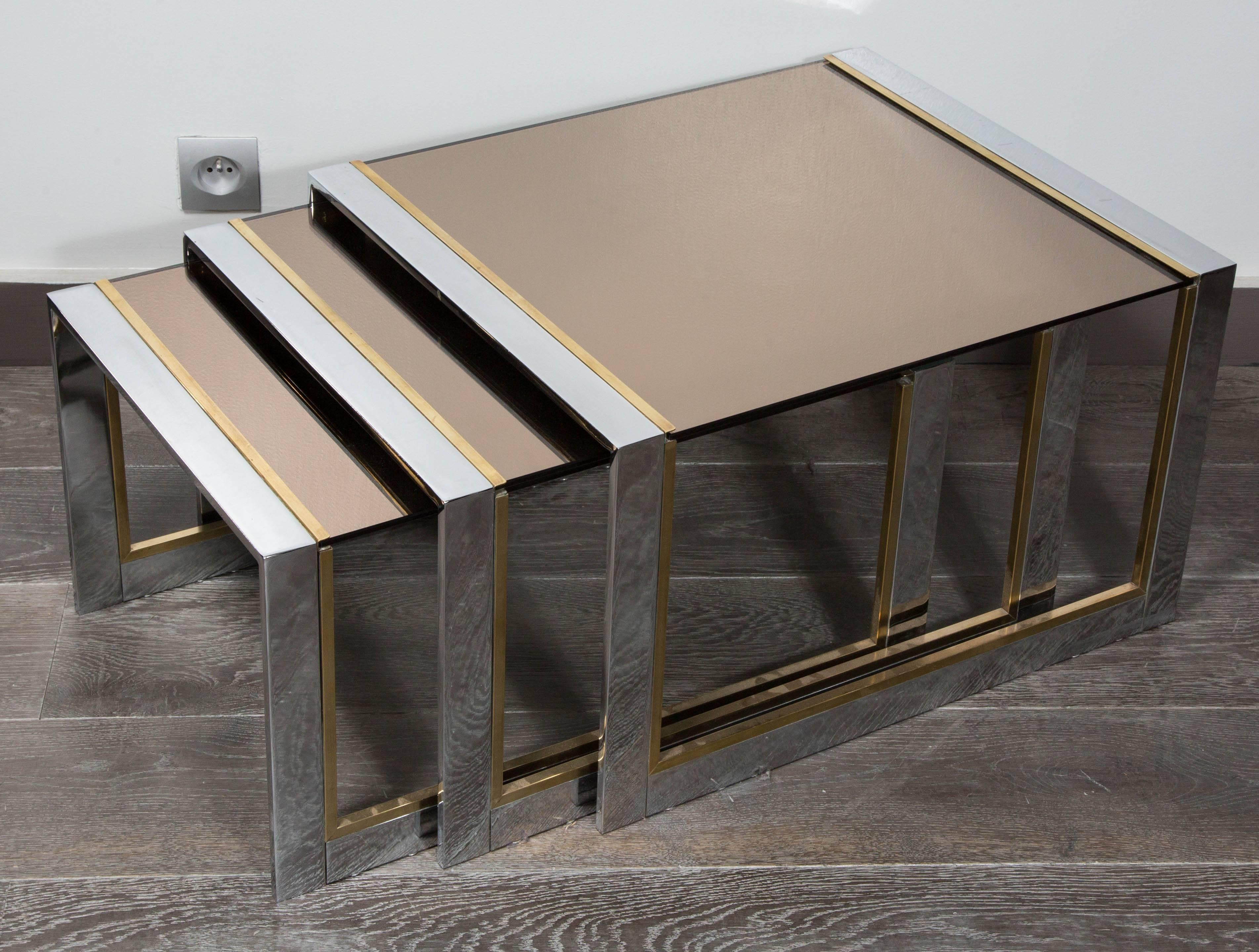 Nesting table in steel and brass with top glass.
France, circa 1970.