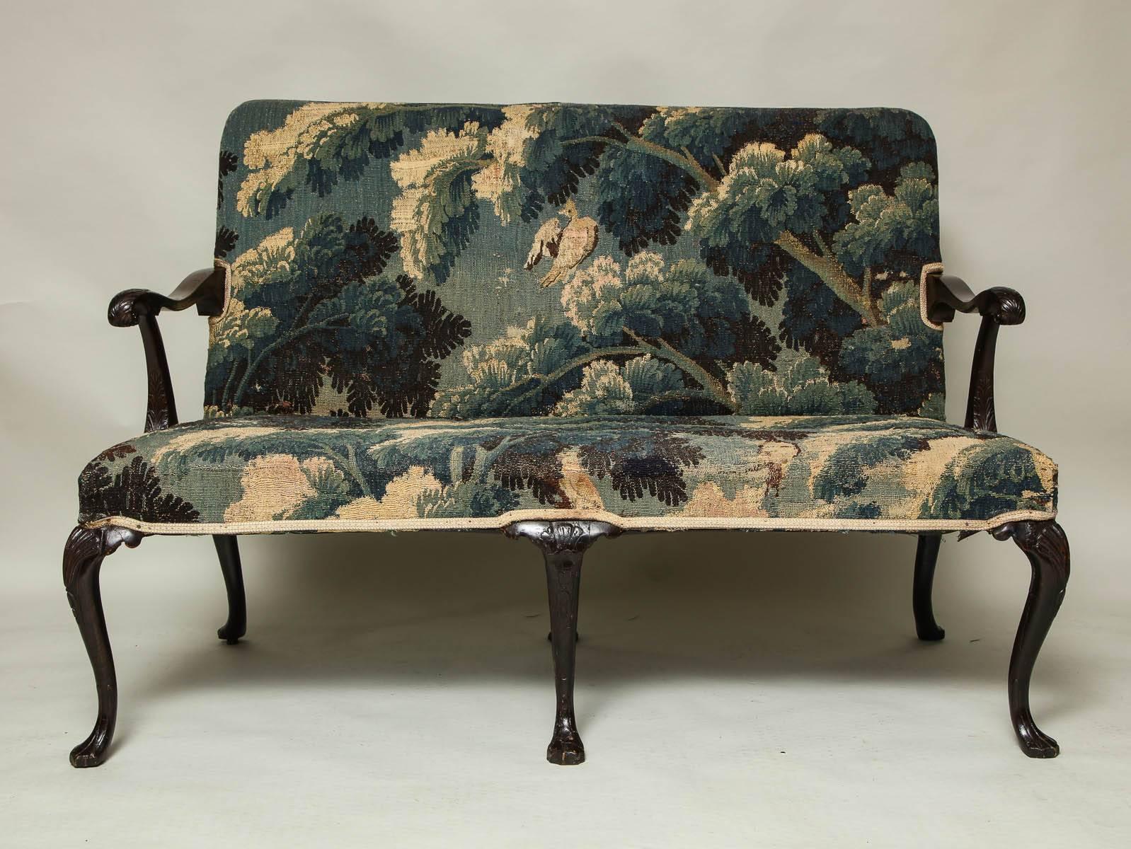 A very fine George II mahogany settee, the acanthus carved arms with finely scrolled ends, standing on shell and bell flower carved cabriole legs ending in Drake feet. Upholstered in 17th century Flemish tapestry, Irish, circa 1750.
 