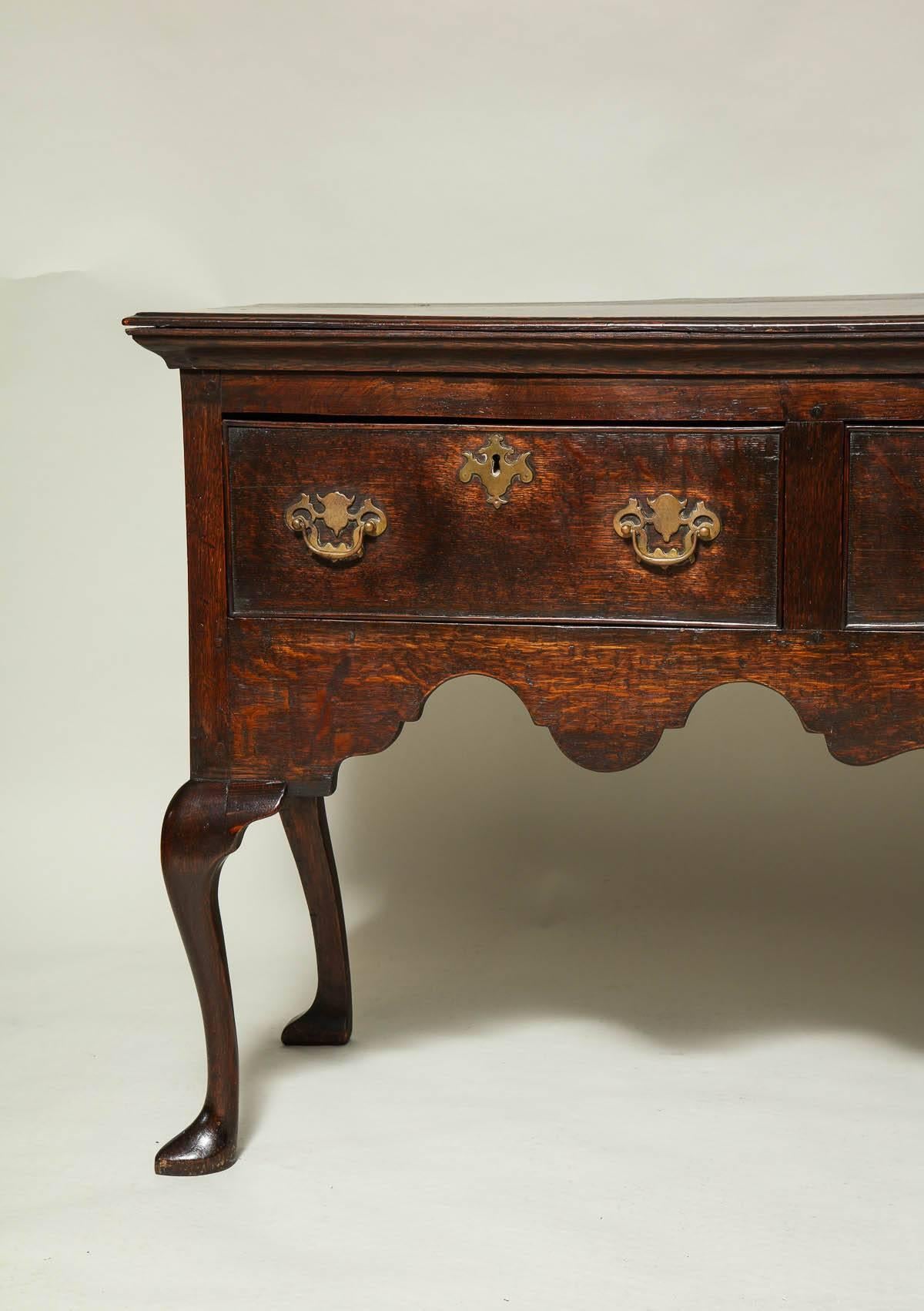 Good 19th century Welsh low dresser with rich molded detail under the top, over three drawers with original pierced brasses over richly scalloped apron and standing on cabriole legs ending in slipper feet.