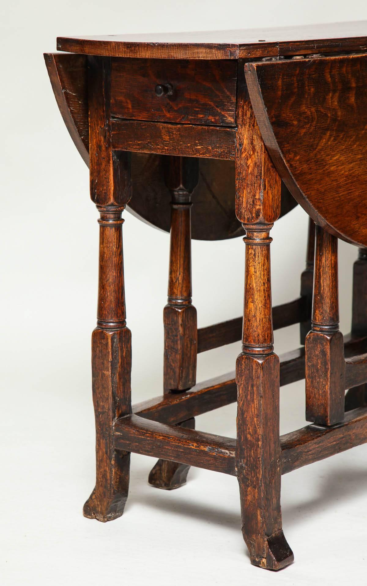 Good early 18th century English oak gateleg table of diminutive scale, the oval top with square edge over single drawer, over cannon barrel turned balustrade legs joined by box stretcher, the feet with unusual swept toe and the whole with good, rich