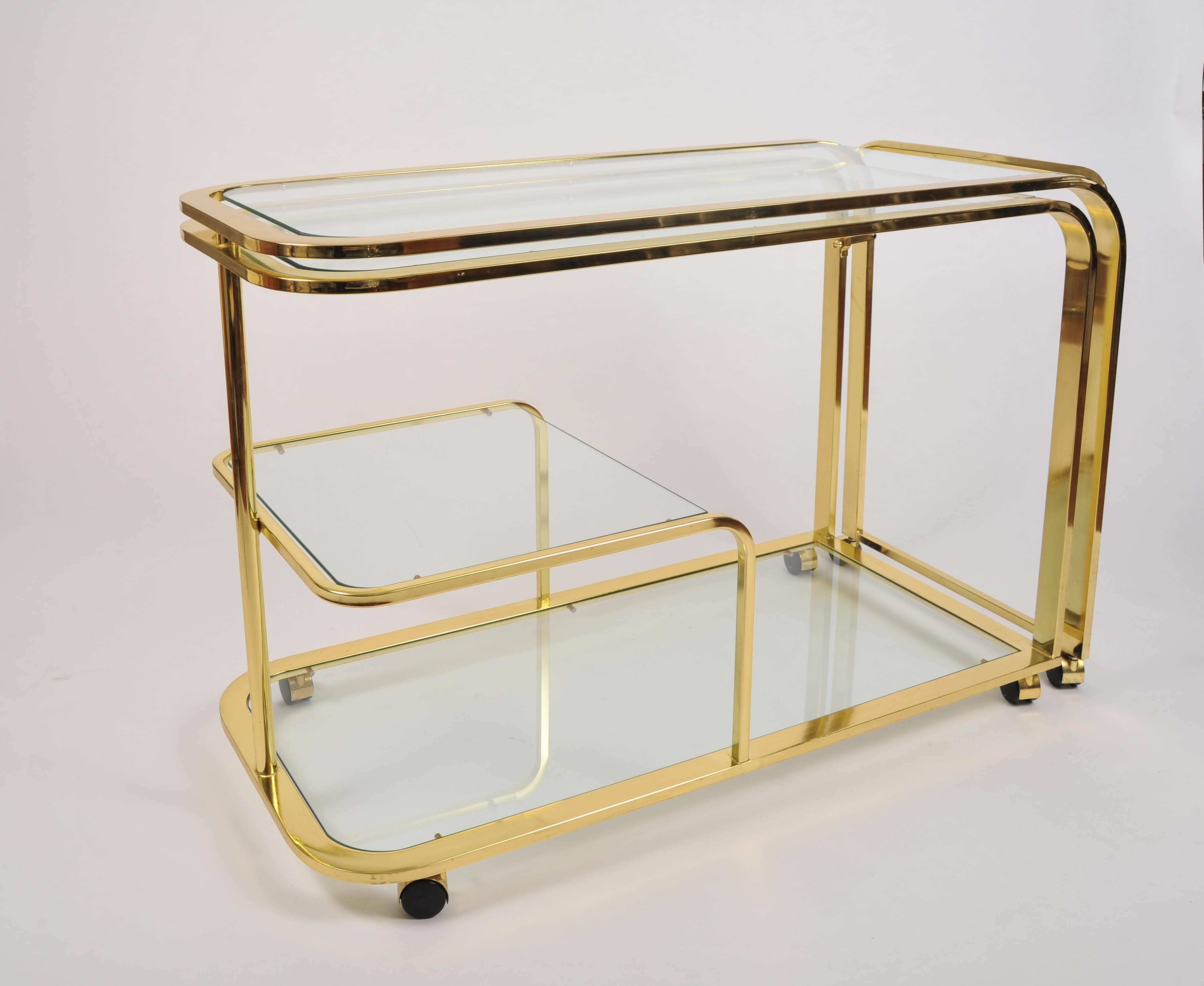 Versatile and chic large brass curved drinks/entertaining trolley which opens to double the length, giving a maximum of four glass shelves. Brass casters allow for easy movement.
