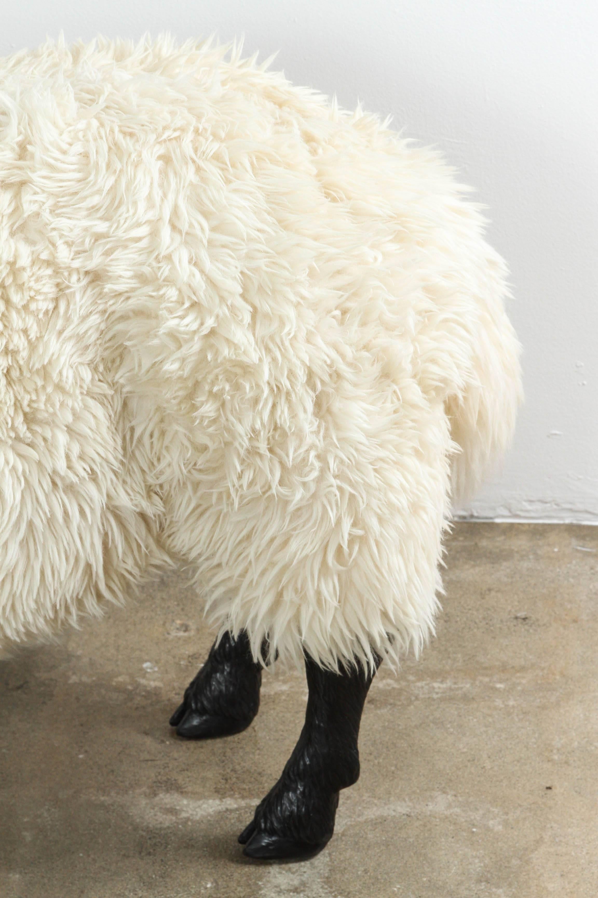 Off-white sheepskin bench on solid bronze sculpted legs. 
Rubber anatomical detail under sheep tails.