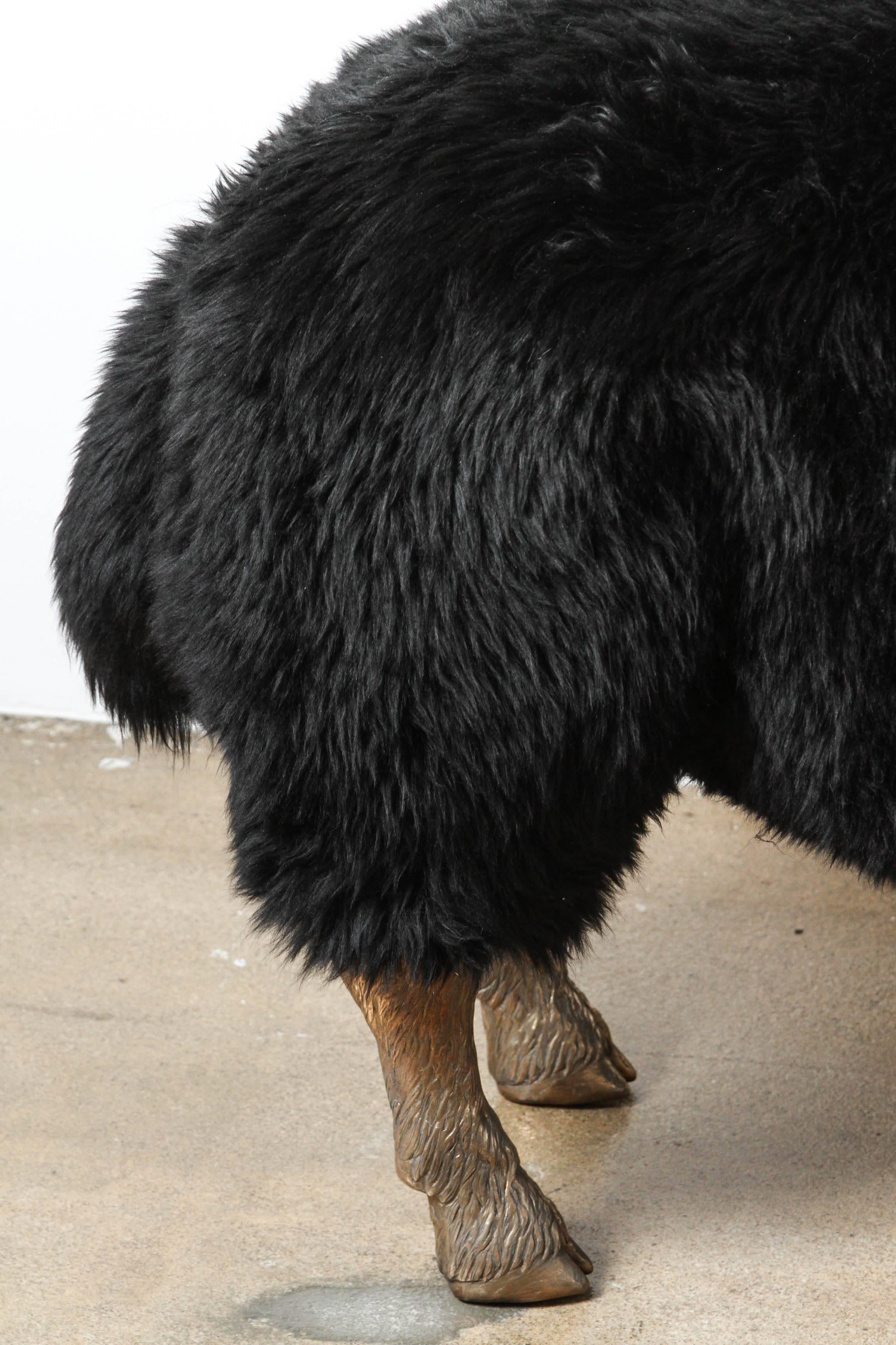Black sheepskin bench on solid bronze sculpted legs. 
Rubber anatomical detail under sheep tails.