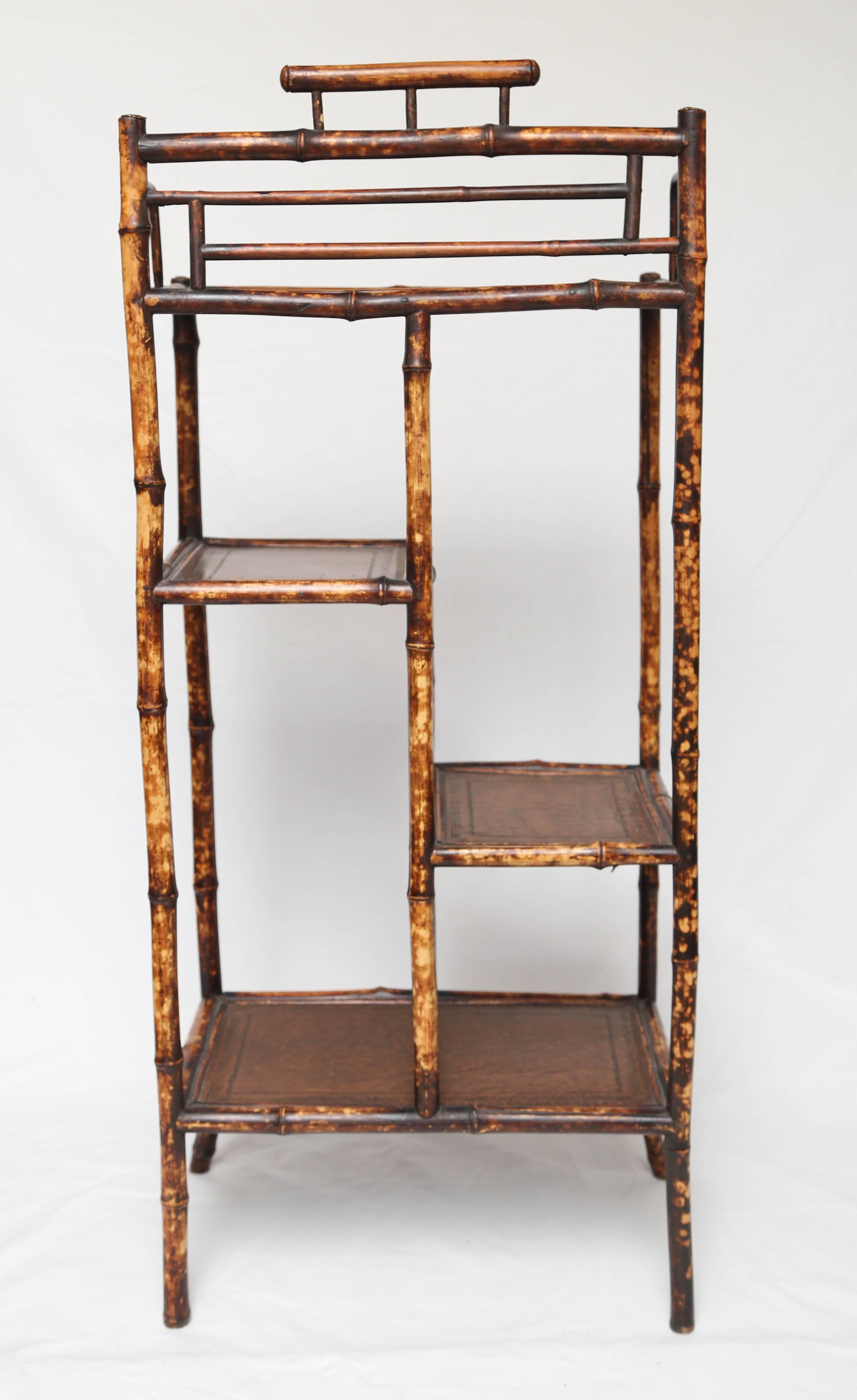 Very sweet tortoiseshell 19th century English bamboo etagere with embossed leather tops. All original.