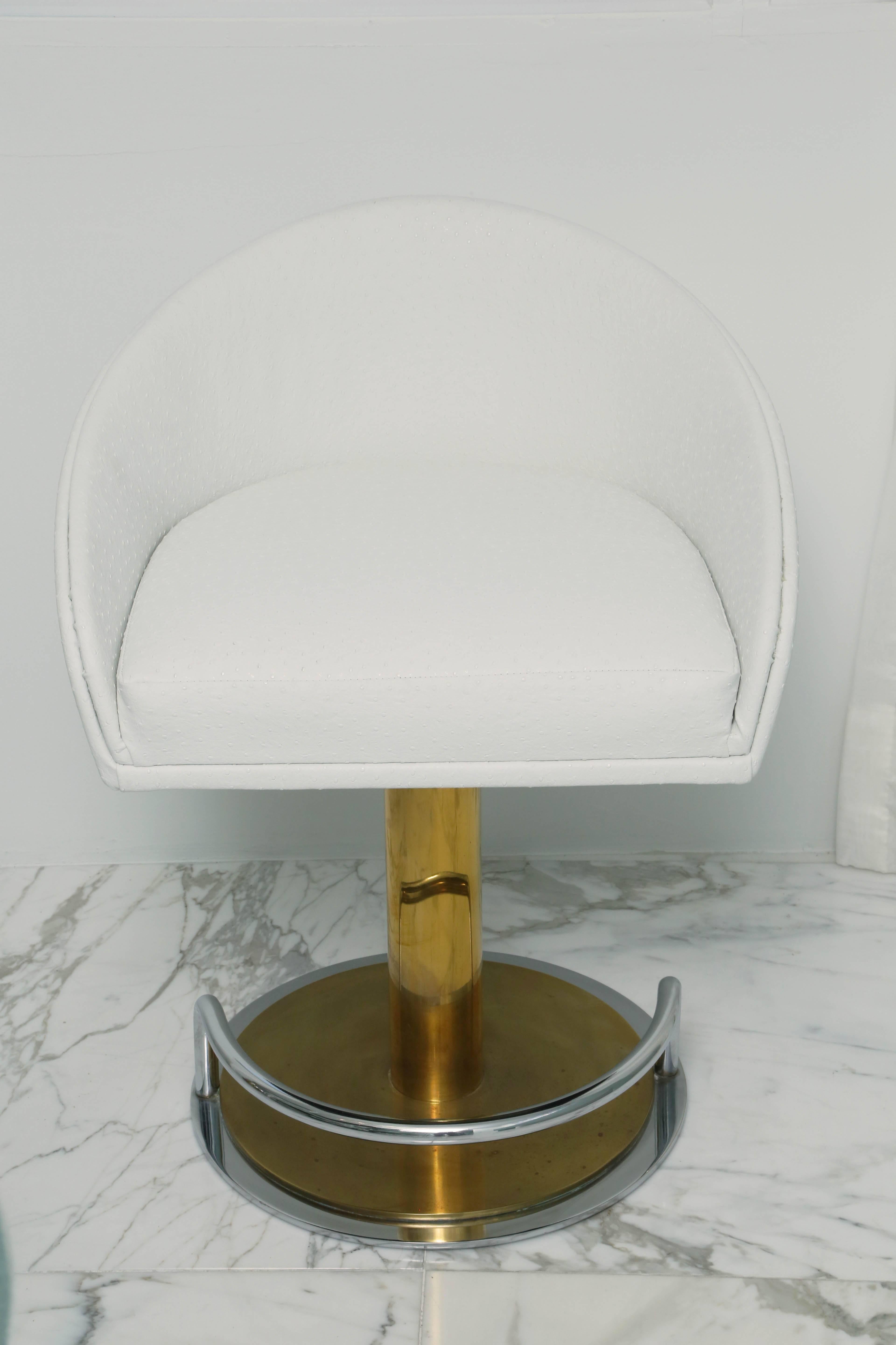 Each newly upholstered in white faux ostrich leather; each swivel seat raised on a gold-toned metal columnar support on a round base with foot support.