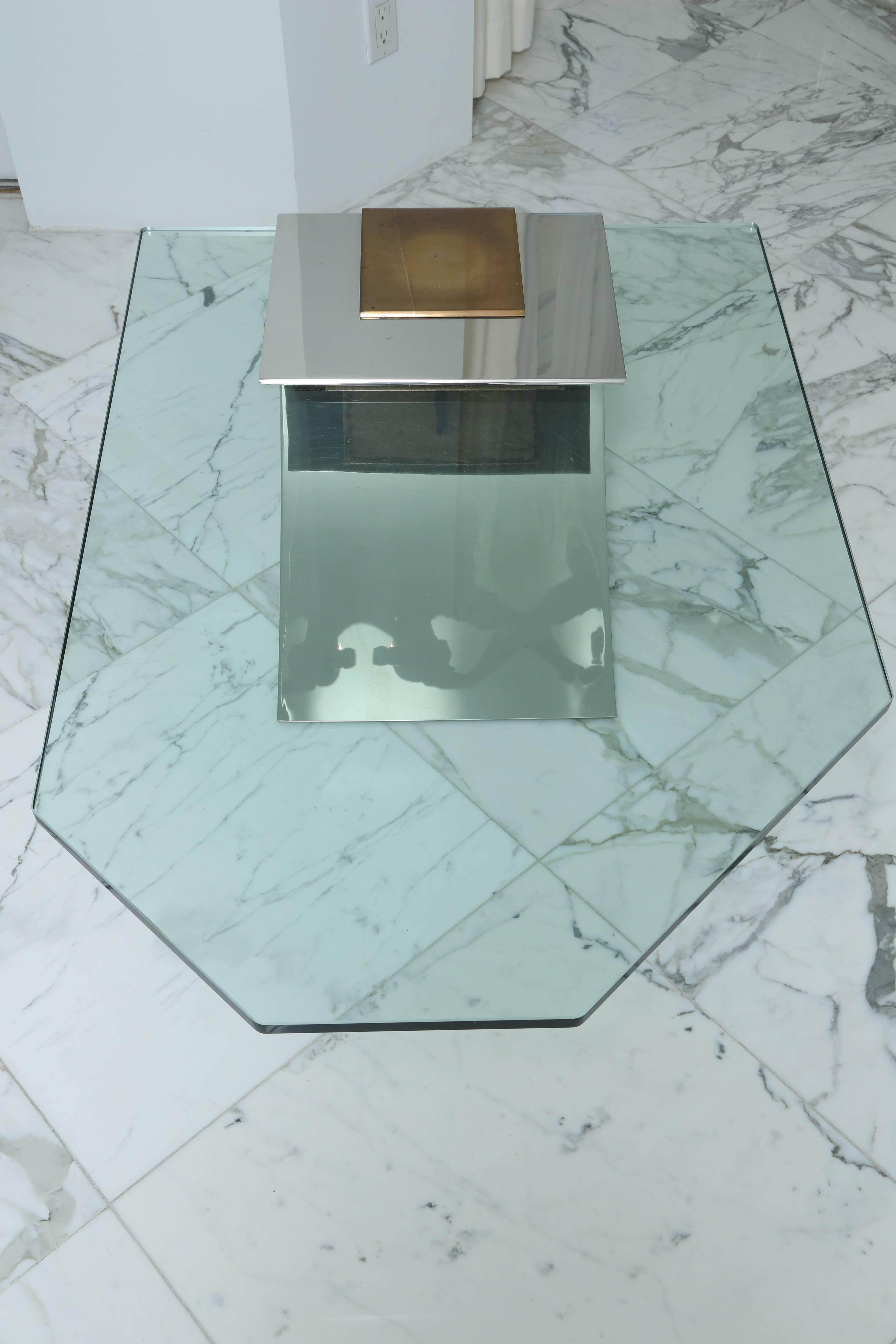 The faceted glass plate top secured by a brass and chrome clasp over the chrome cantilevered support.