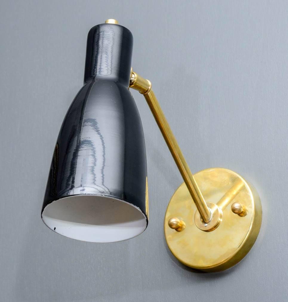 Set of four wall sconces made of a brass structure and a simple black cone holding one source of light. Discreet, this wall sconces will be ideal for bedsides or libraries.