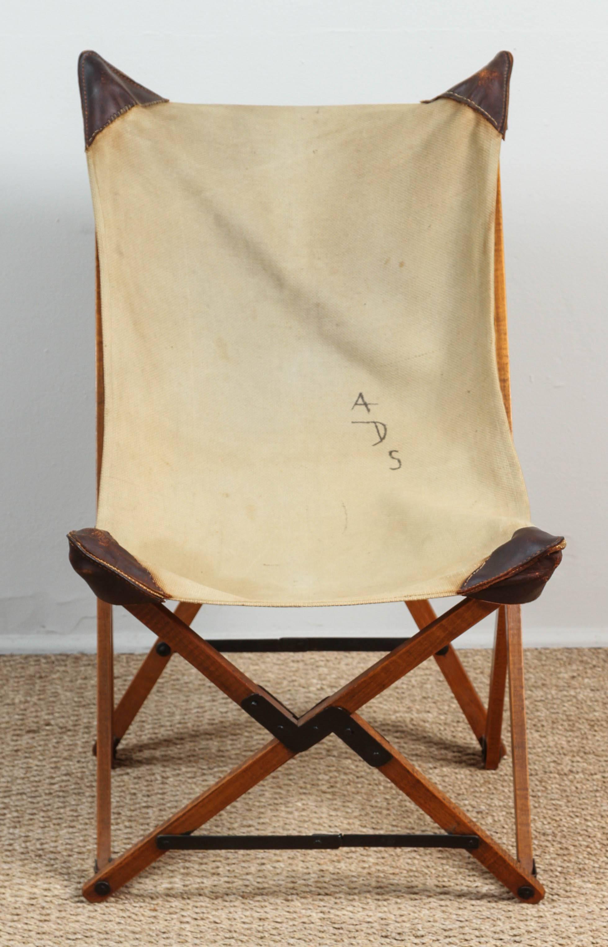 Campaign chair with original heavy canvas seat. Initials ADS painted on to seat fabric. Leather corners have been hand re-sewn. Wooden base with metal hinges folds into a neat pile of sticks. Surprisingly sturdy.