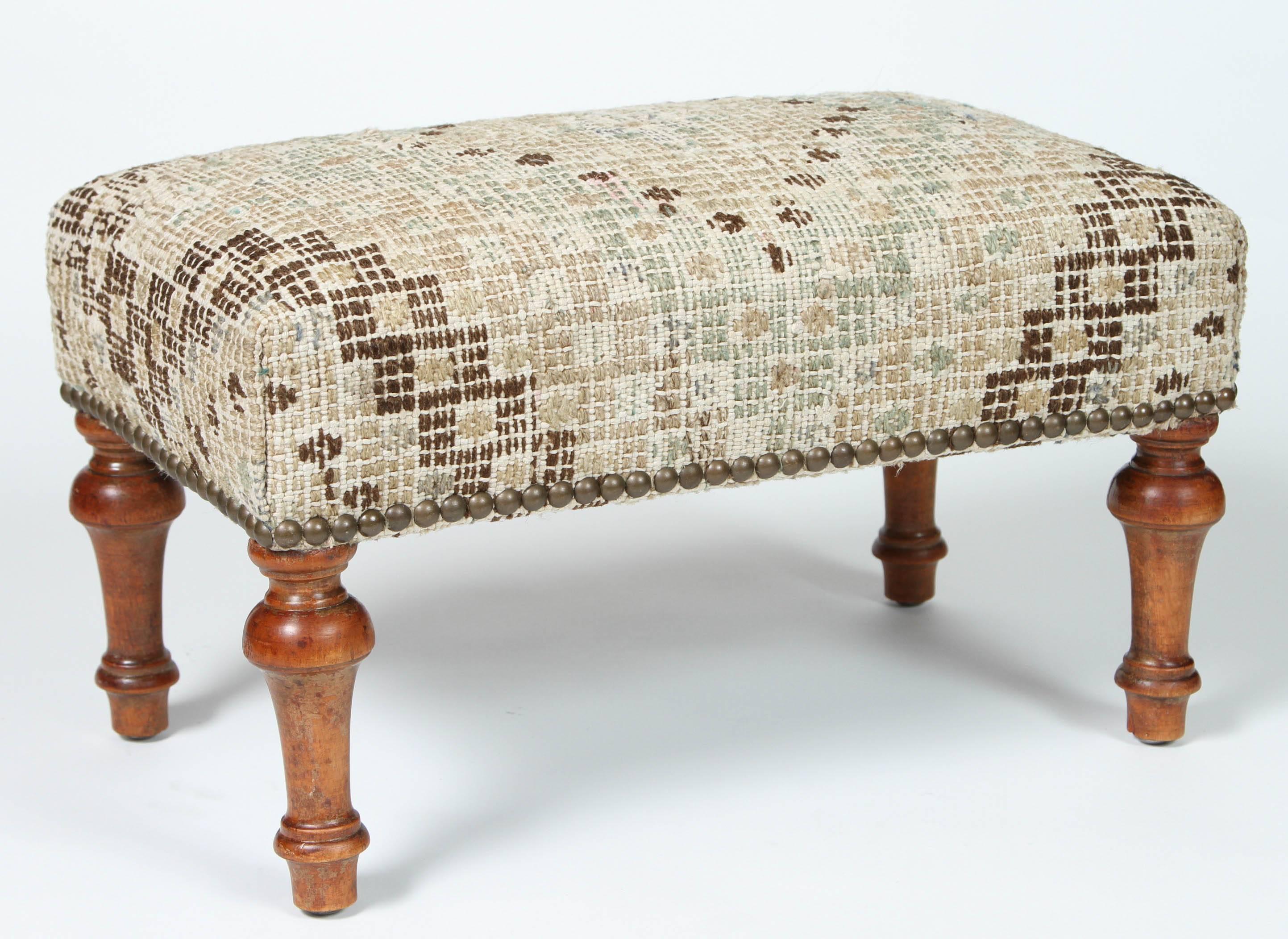 Vintage footstool with turned legs, newly upholstered in Turkish cotton and wool rug with diamond pattern and nailhead trim.