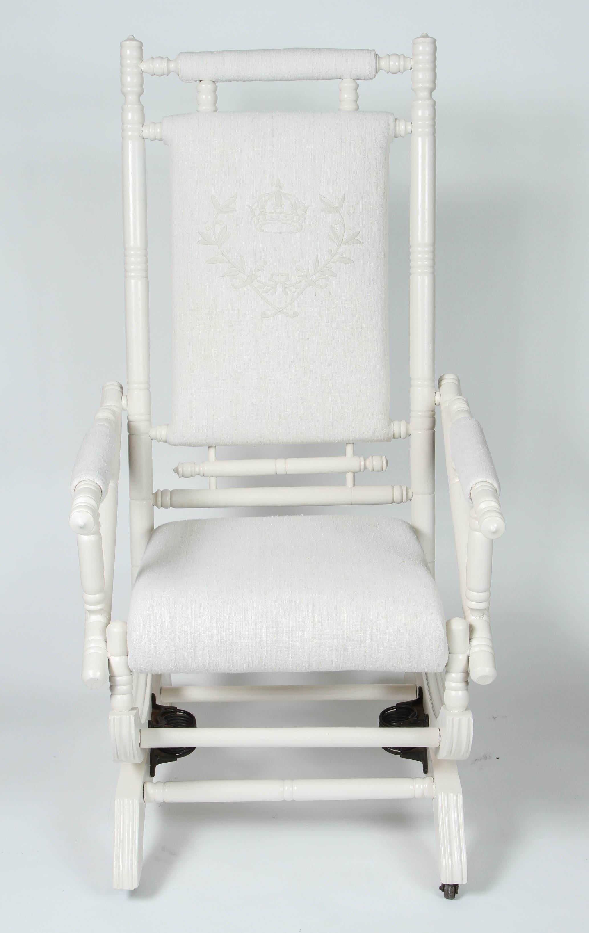 Chaise à bascule antique à ressort avec une nouvelle finition peinte. Il a été nouvellement tapissé en lin Vintage, le dossier ayant été brodé sur mesure d'une couronne et d'un écusson.