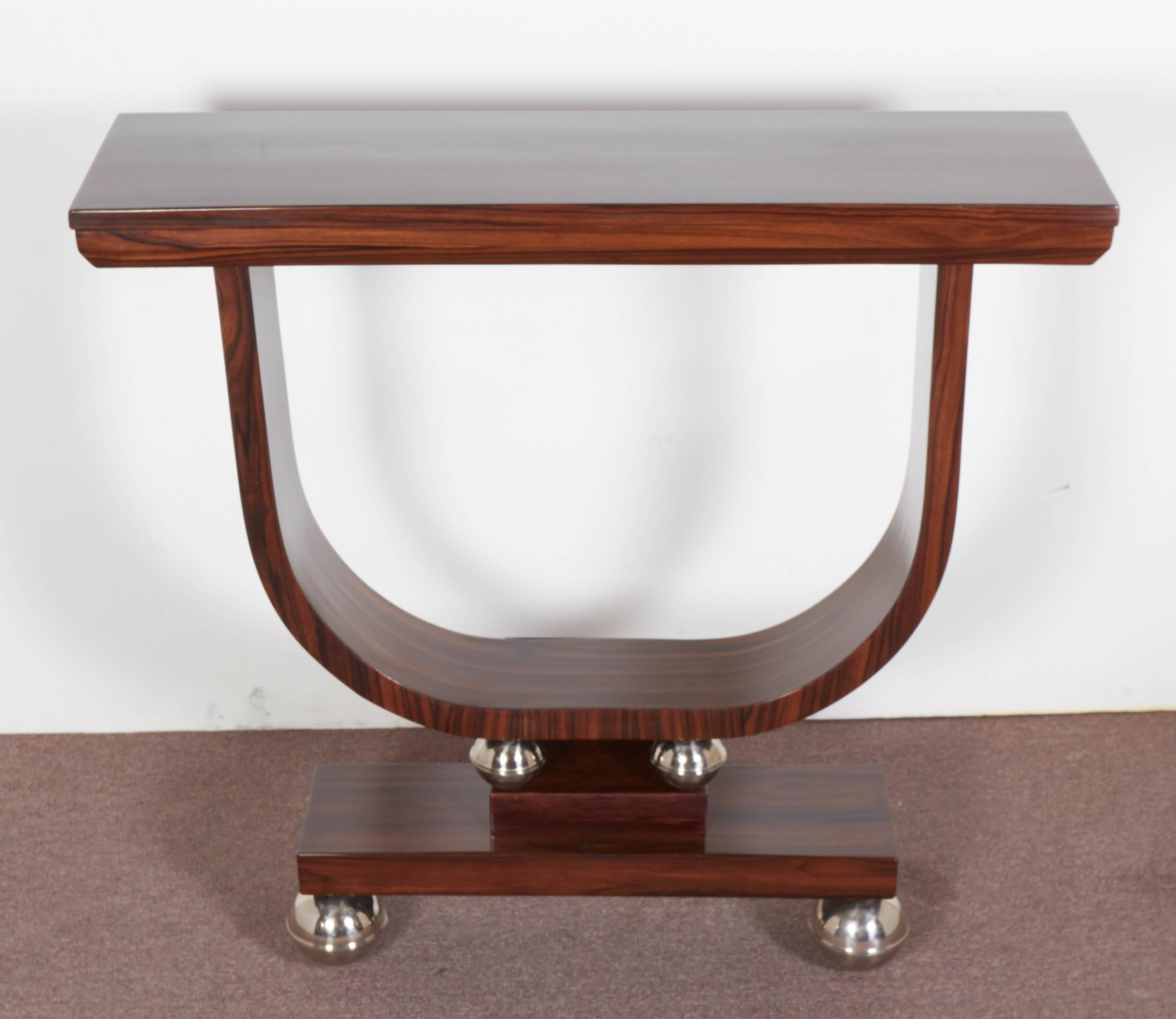 Modernist exotic Macassar ebony sculptural U shaped console raised on stepped plinths with nickeled metal ball accents.
This U-shape is a graceful design element, typical of the Art Deco period.
The console has a very proper height of 33 1/2 inches.