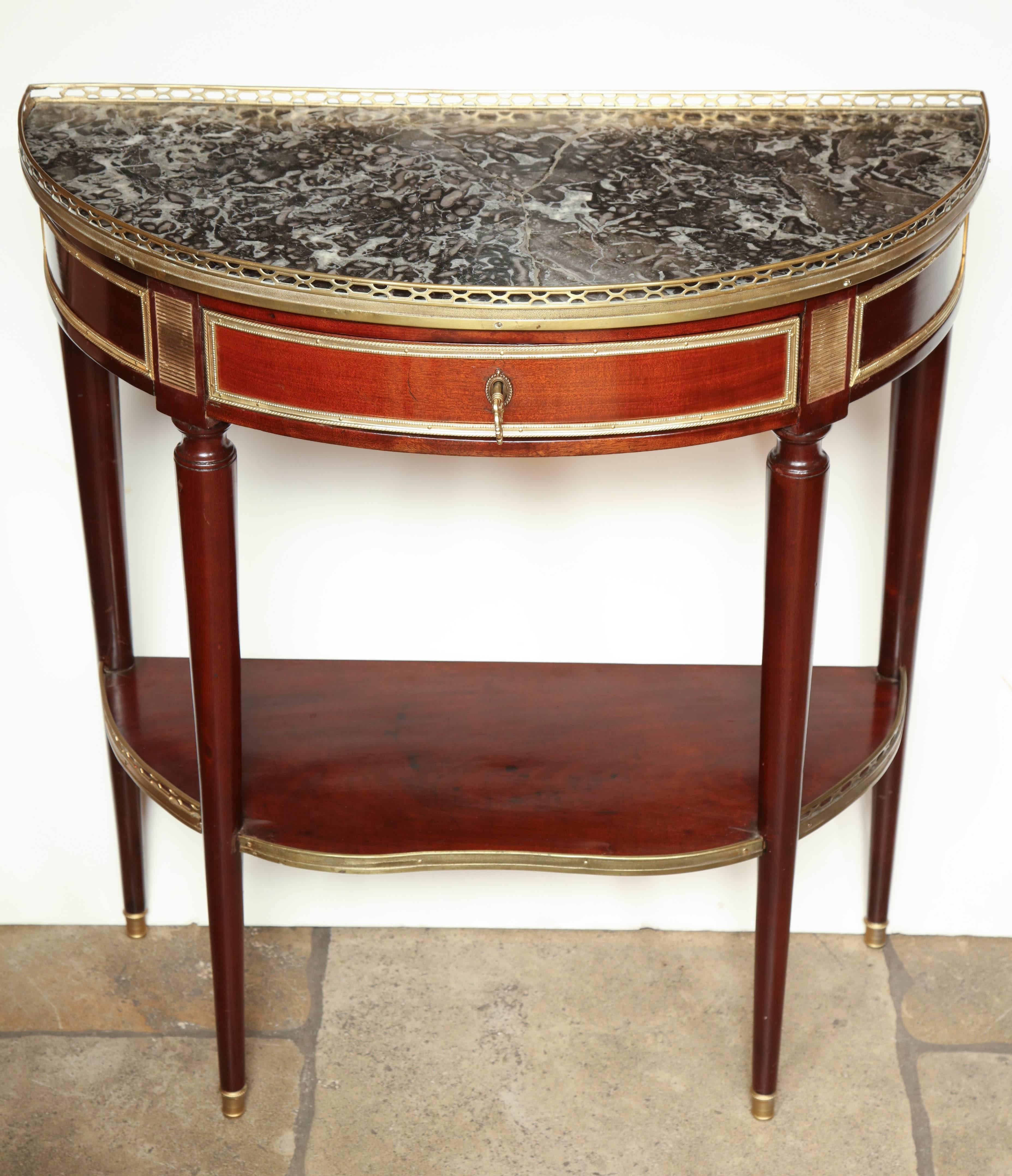 French Louis XVI marble-top mahogany demilune console table. With a pierced bronze gallery, brass mounts and trim, turned and tapered legs and a shelf stretcher base.
Stamped 