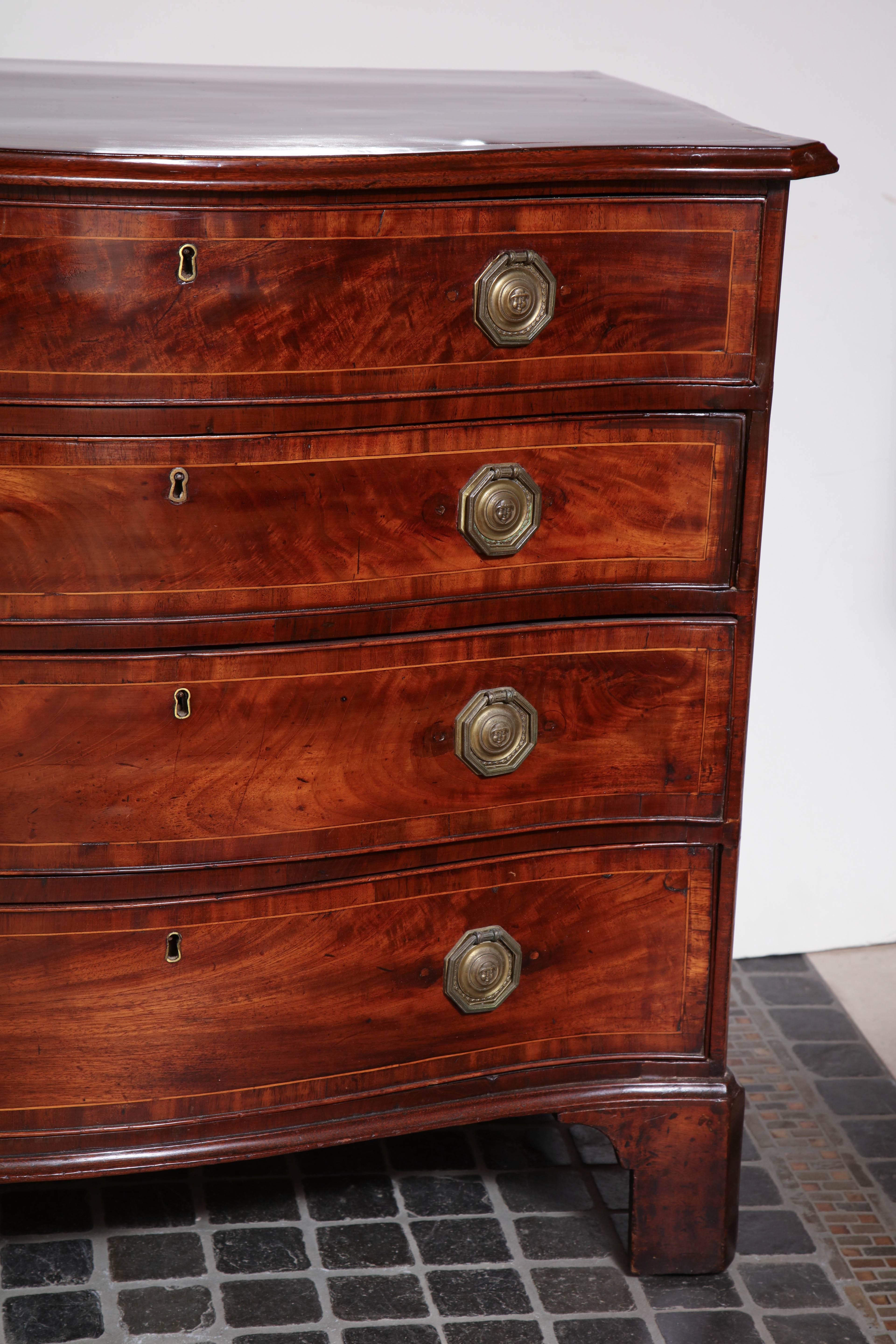 A fine English George III mahogany crossbanded serpentine chest of drawers with molded edge top, graduated drawers and bracket feet.