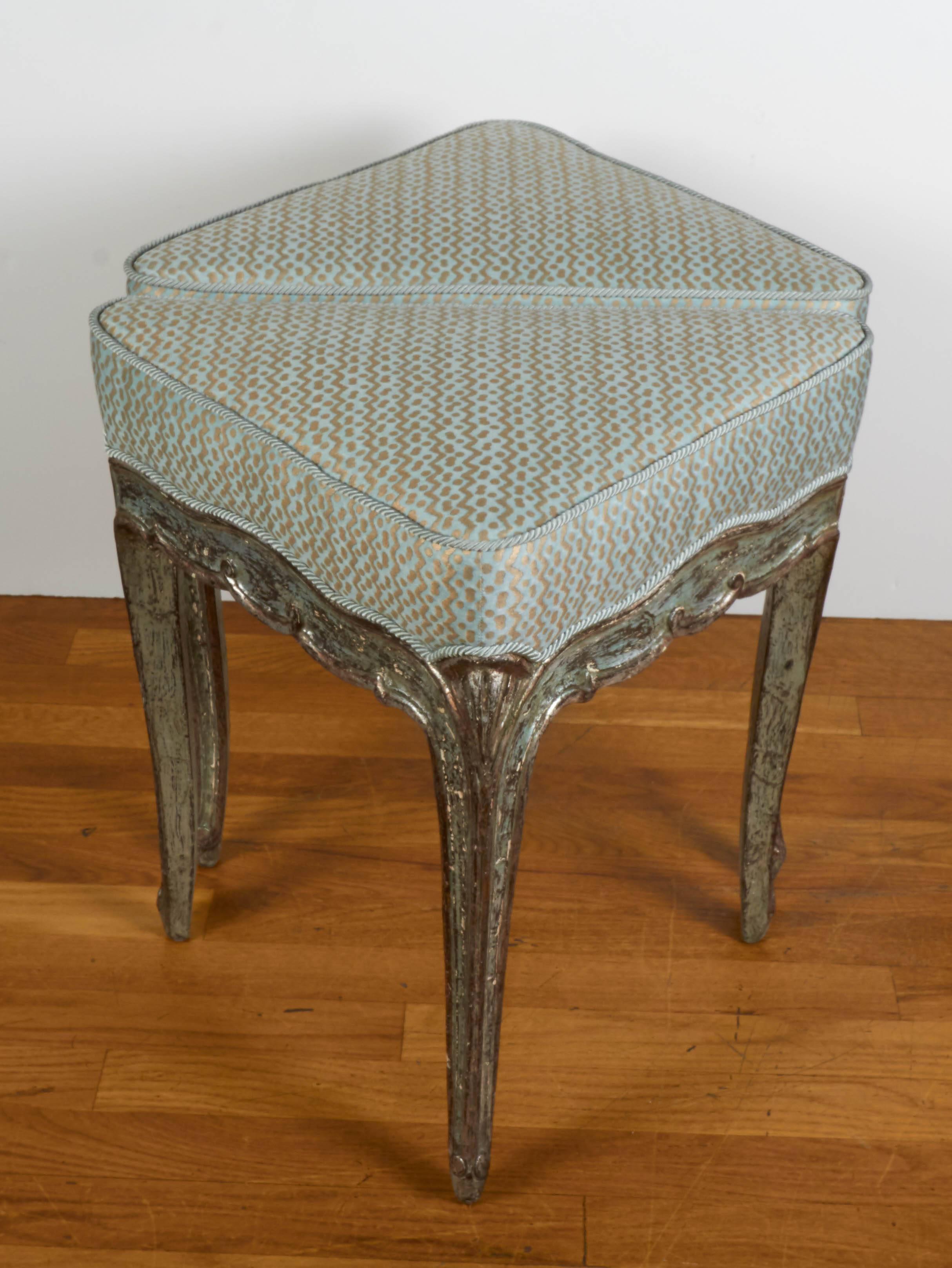 A pair of Italian Rococo style silver leaf benches, triangle form with delicate shell carved knees on cabriole leg, newly upholstered in aquamarine and silver Fortuny fabric in the Tapa pattern