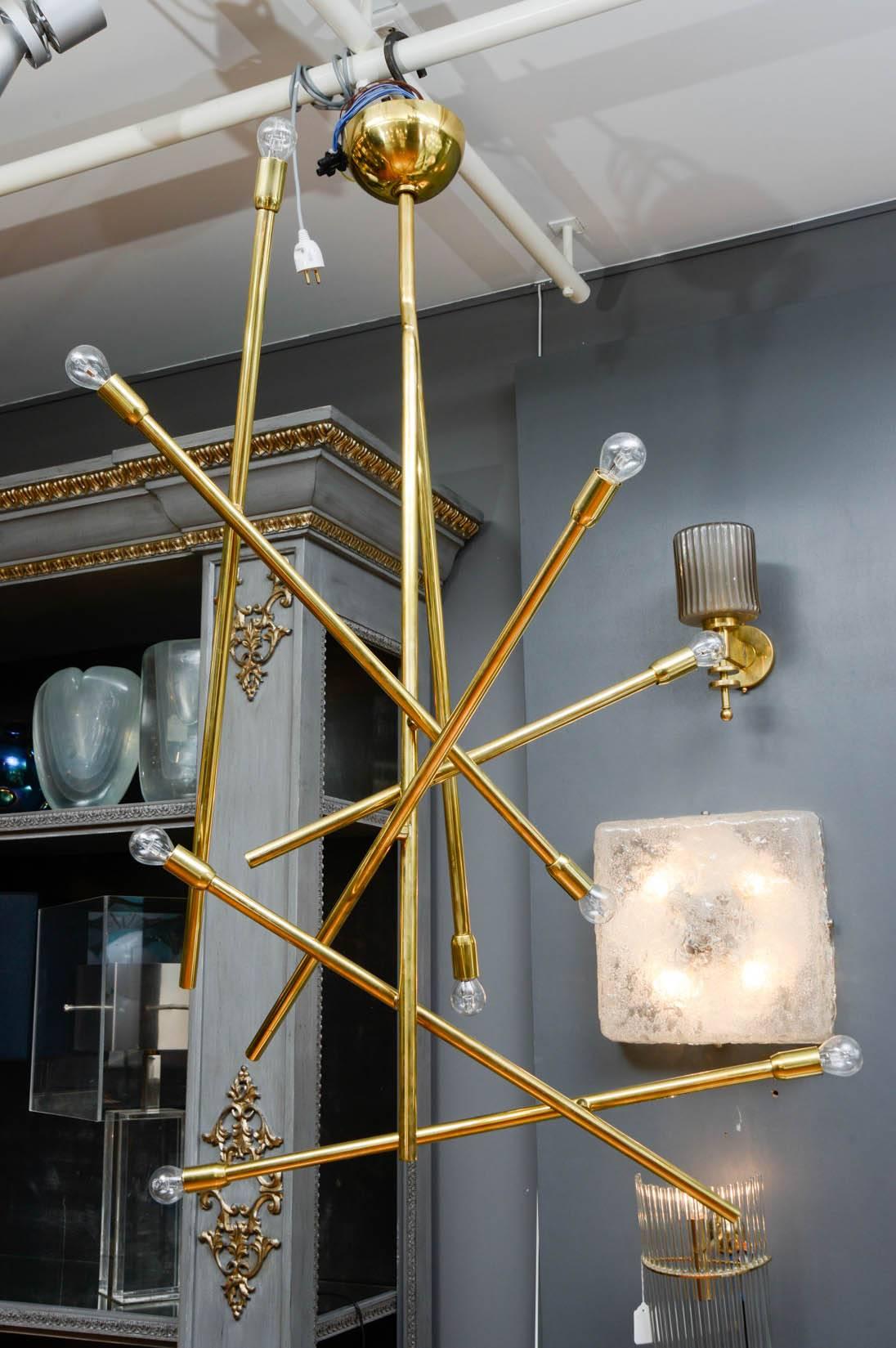Brass chandelier made of a central stem and eight arms of lights giving an asymmetric overall look.