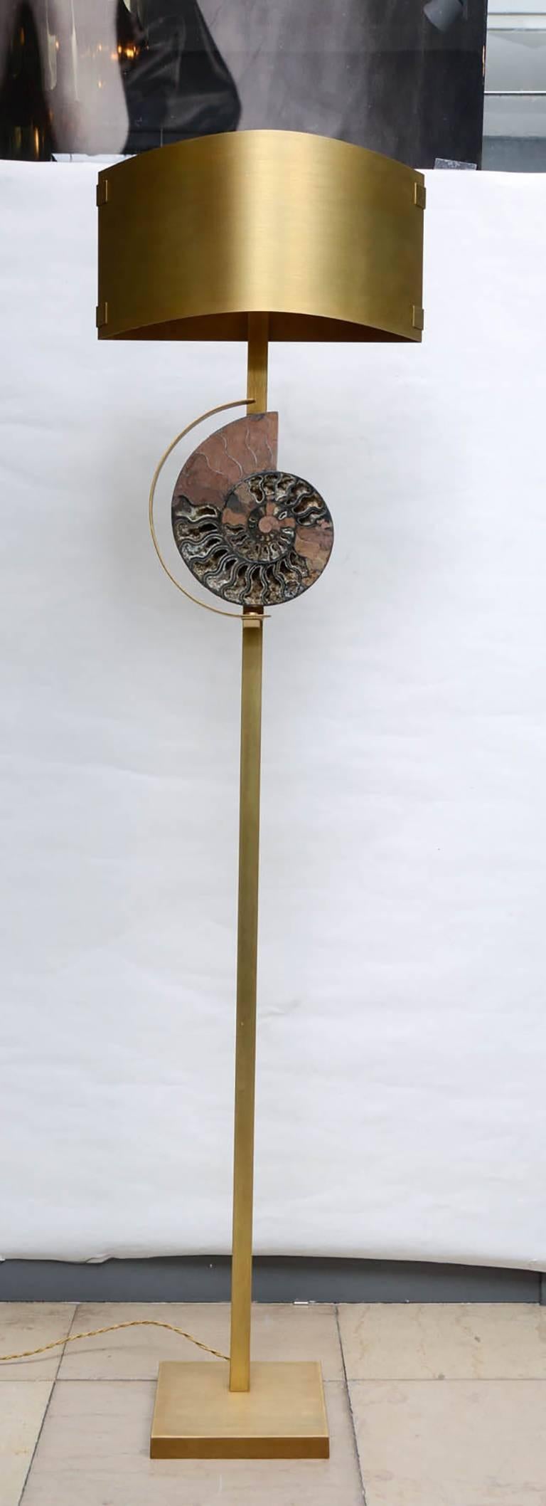 Paire de lampadaires en laiton patiné avec un abat-jour en métal en demi-cercle.
Ammonite de Russie au centre, sertie en France.
Paire unique créée par le Studio Glustin.