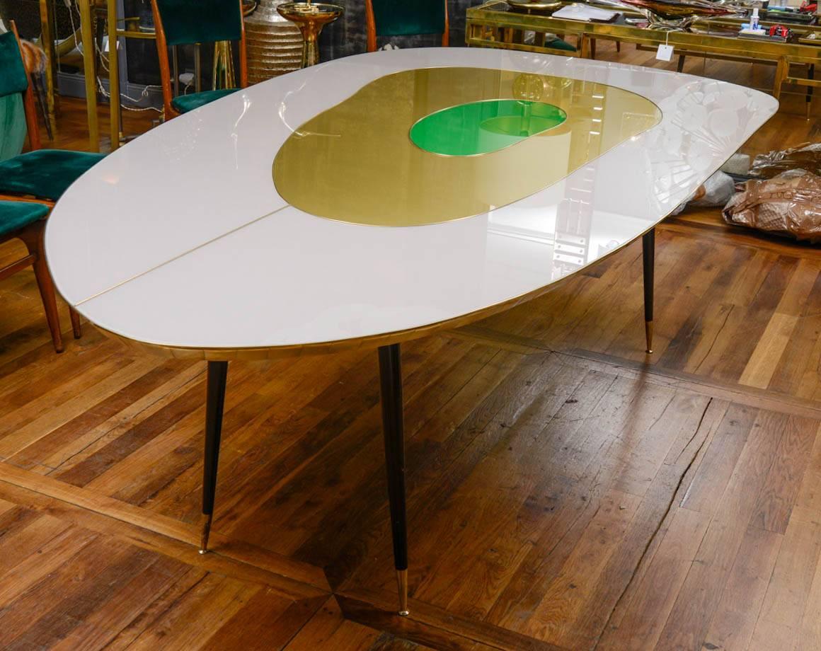 Free shape dining room table, top in tinted glass with brass fillet, legs in metal ending by a brass tip.
Unique Piece made by Studio Glustin
It is possible to change the dimensions and the colors of the top.