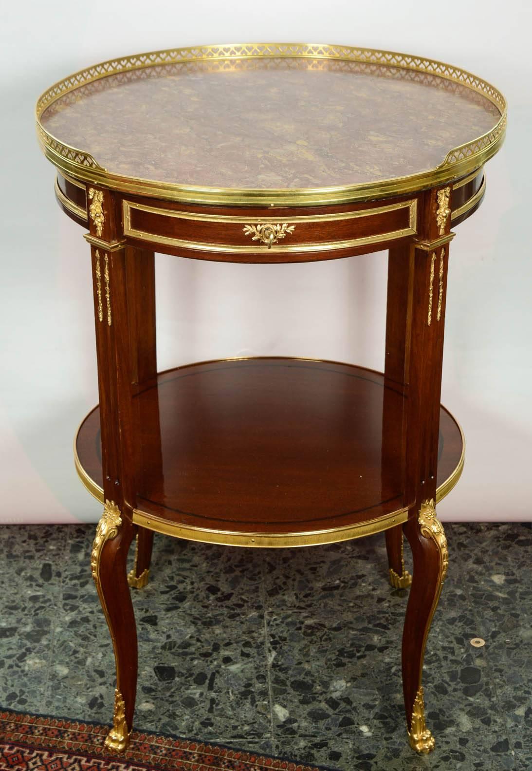 Pair of round tables in varnished mahogany, decorated with gilded bronzes, topped with a marble breche, one drawer in the belt.