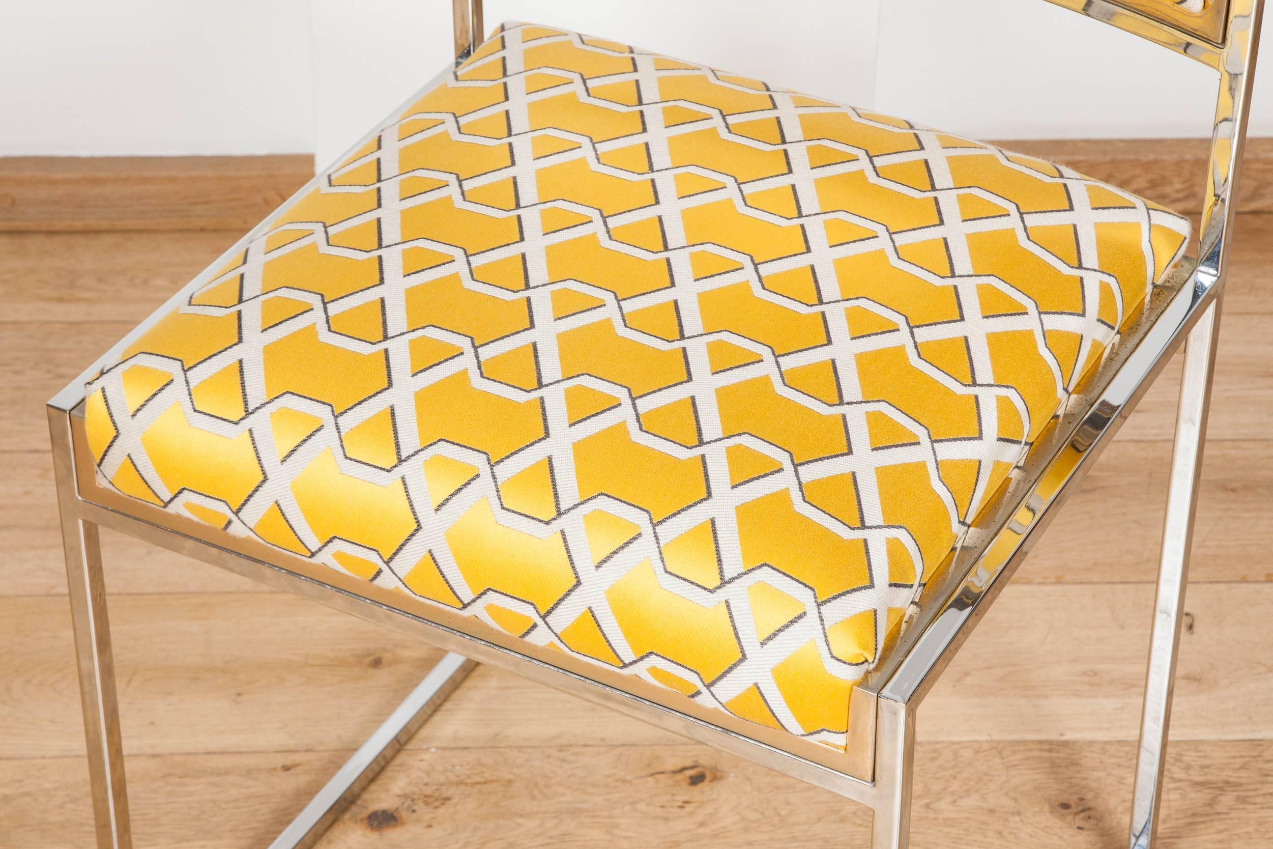 Polished metal edged in brass dining chairs, re-upholstered in yellow fabric with geometric pattern.