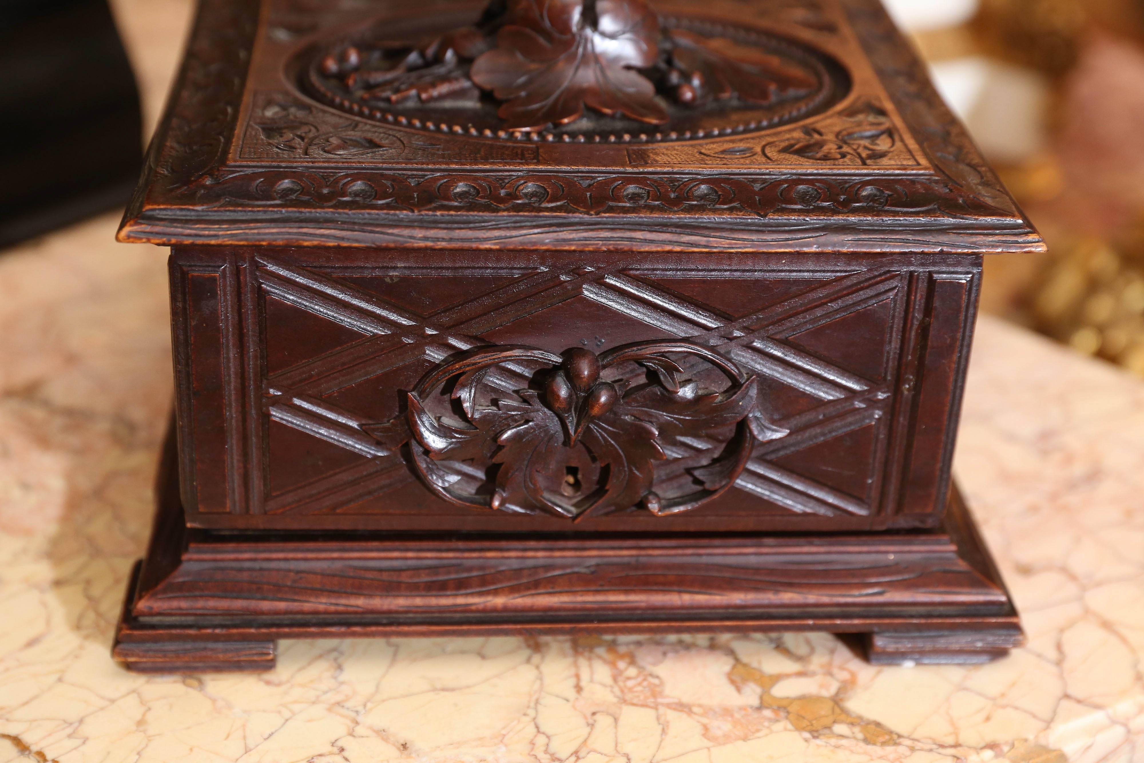Black Forest fitted cigar box, 19th century, relief oak leaves carved in the top
centre the lift top, further detailed with ivy vines and foliate border, a diamond
Pattern on the case, opening to three pull-out cigar trays.