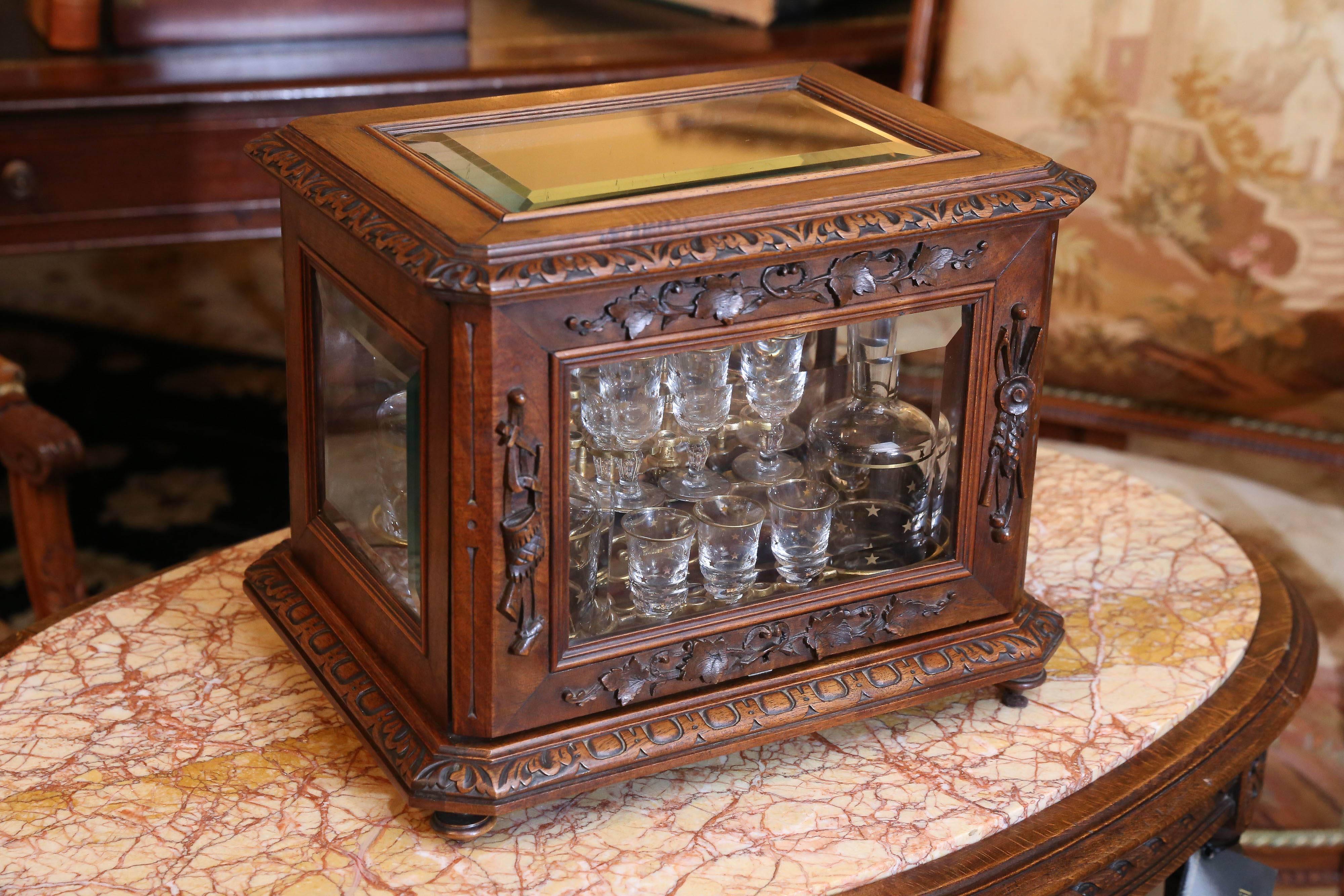 French carved walnut box and beveled glass holding a set of four decanters 
And 16 liqueur glasses. The top and sides are beveled glass.