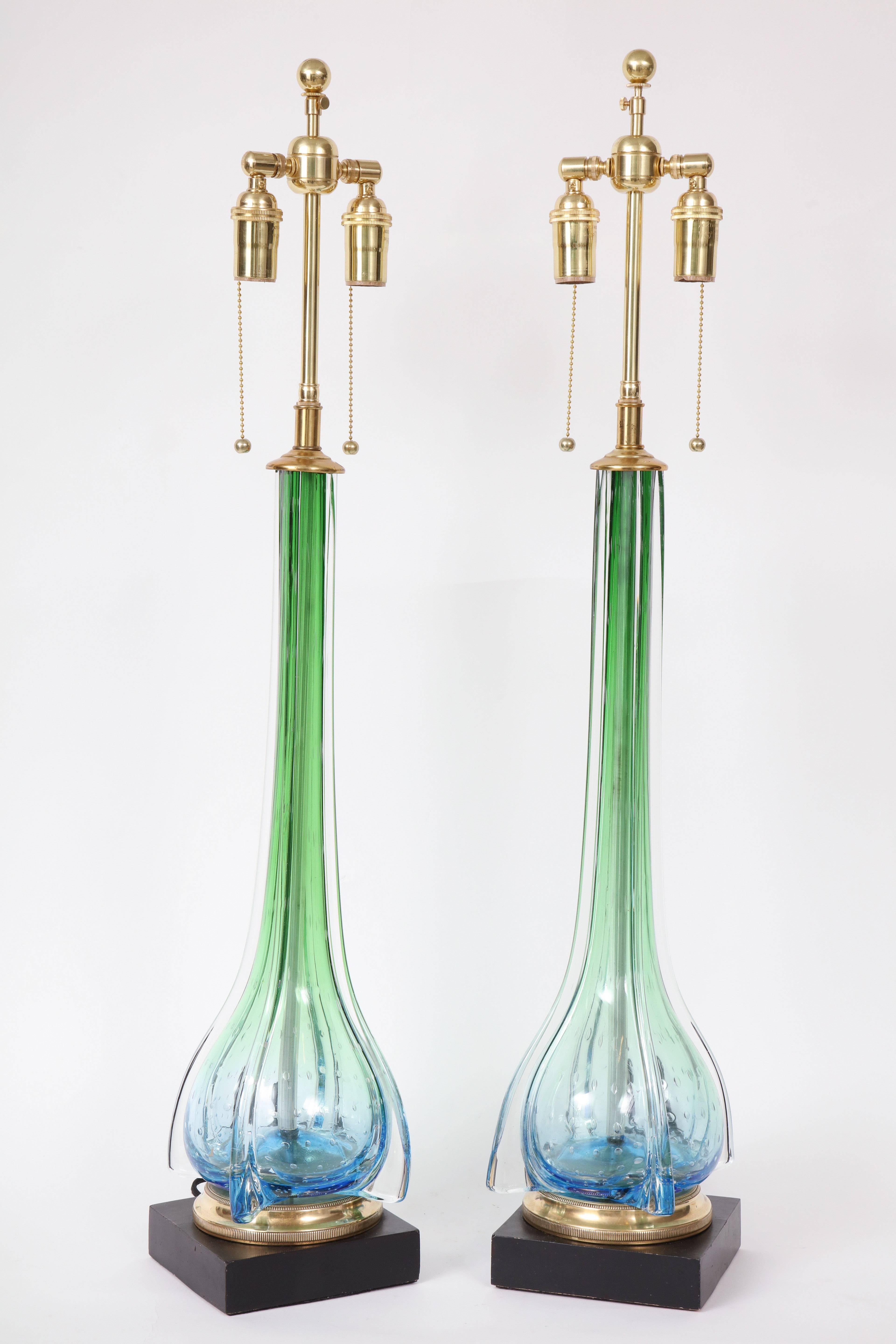 Beautiful pair of Murano lamps by Seguso.
These handblown glass lamp bodies are in exquisite shades of Green and blue.
They have controlled bubbles towards the bottom where the base is mounted onto a polished brass base which sits on top of a