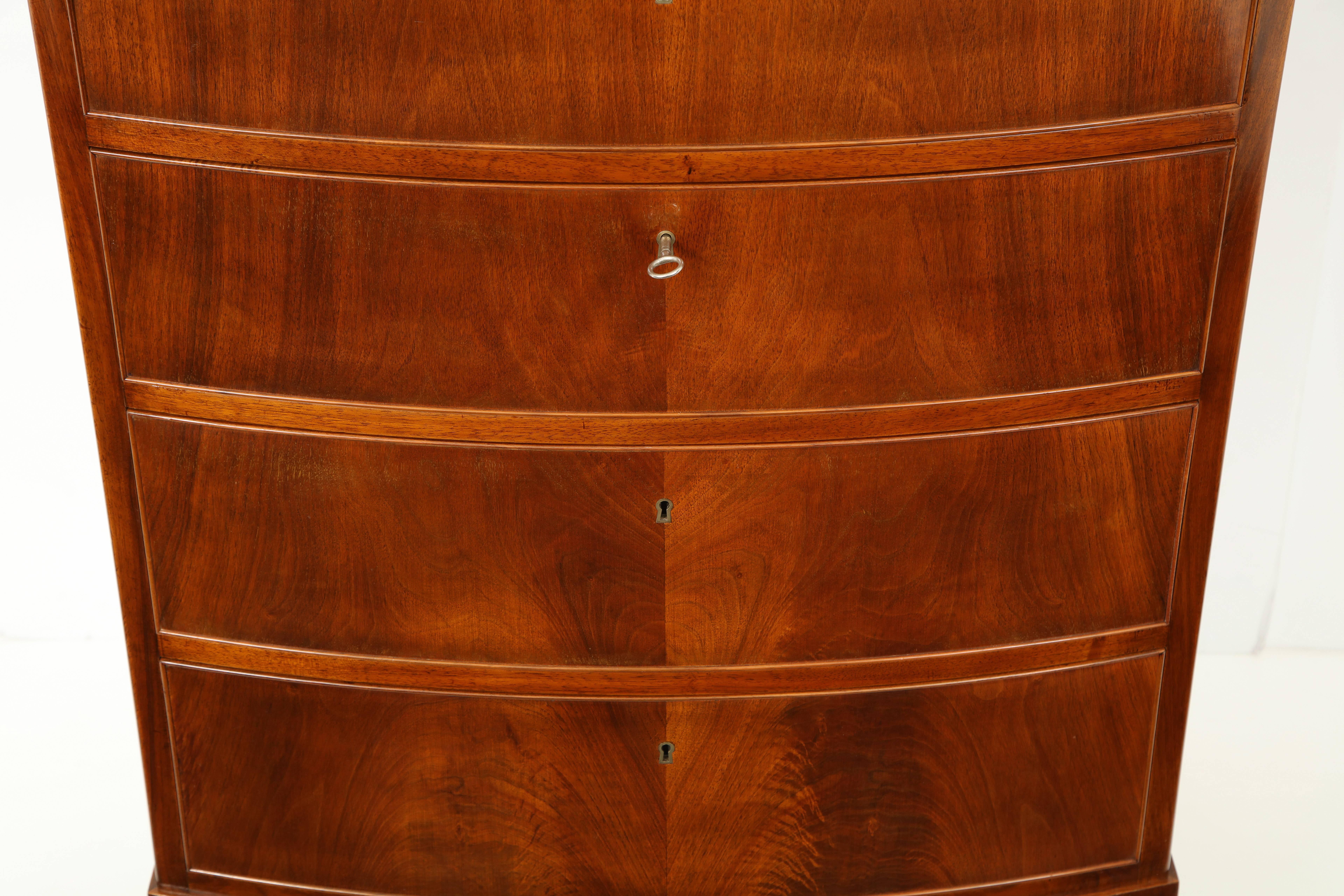 An elegant Frits Henningsen figured mahogany chest of drawers, circa 1940s, with six bow-fronted graduated drawers raised on square tapered legs with block feet. An excellent example of the understated cabinetmaking skills of the Danish designer and