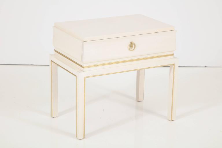 Pair of Tommi Parzinger Mid-Century bleached maple side tables/ nigh stands with satin brass pulls, trimmed in 22-karat gold leaf detailing around legs and perimeter of cabinet. Stamped