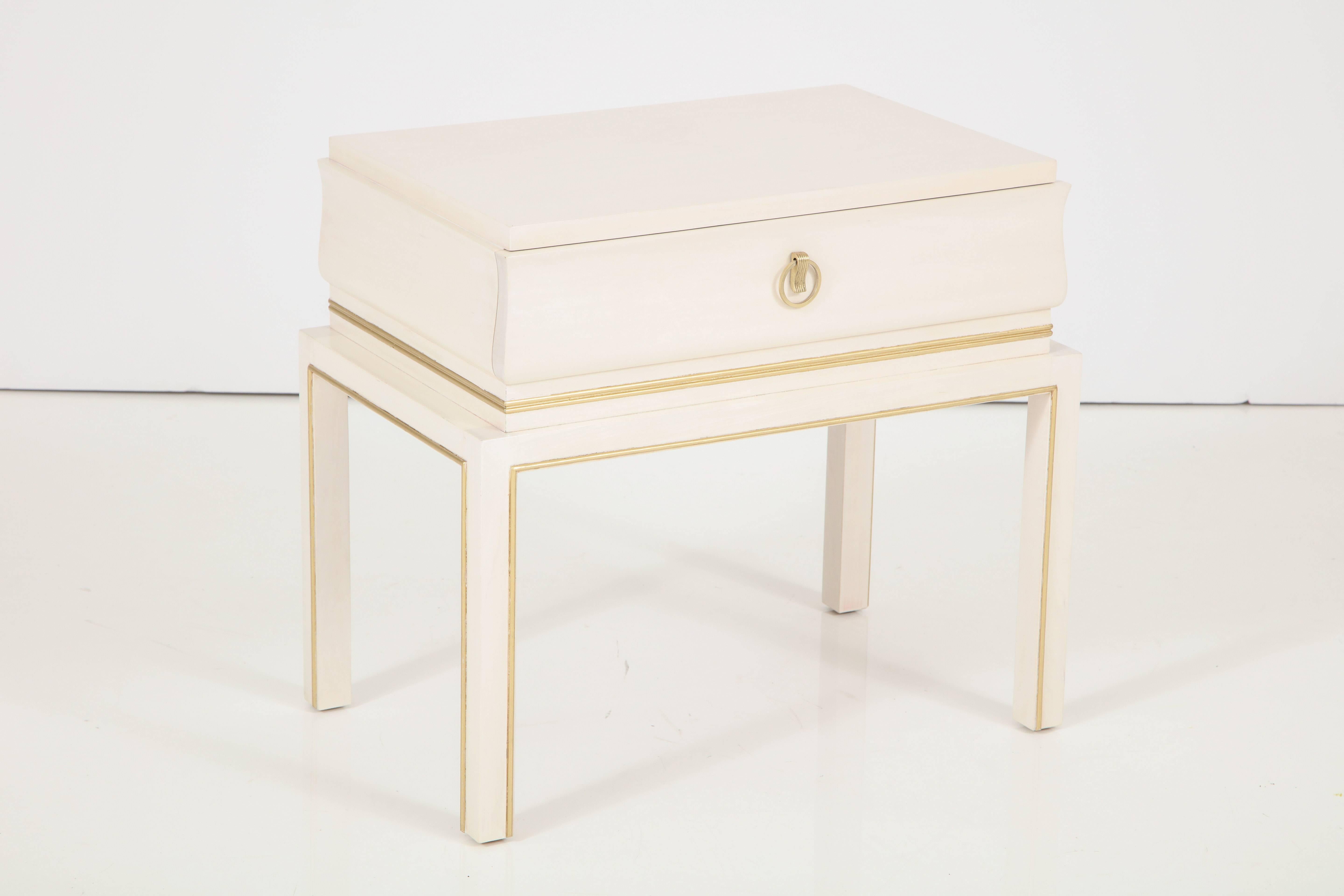 Pair of Tommi Parzinger midcentury bleached maple side tables/ nigh stands with satin brass pulls, trimmed in 22-karat gold leaf detailing around legs and perimeter of cabinet. Stamped.