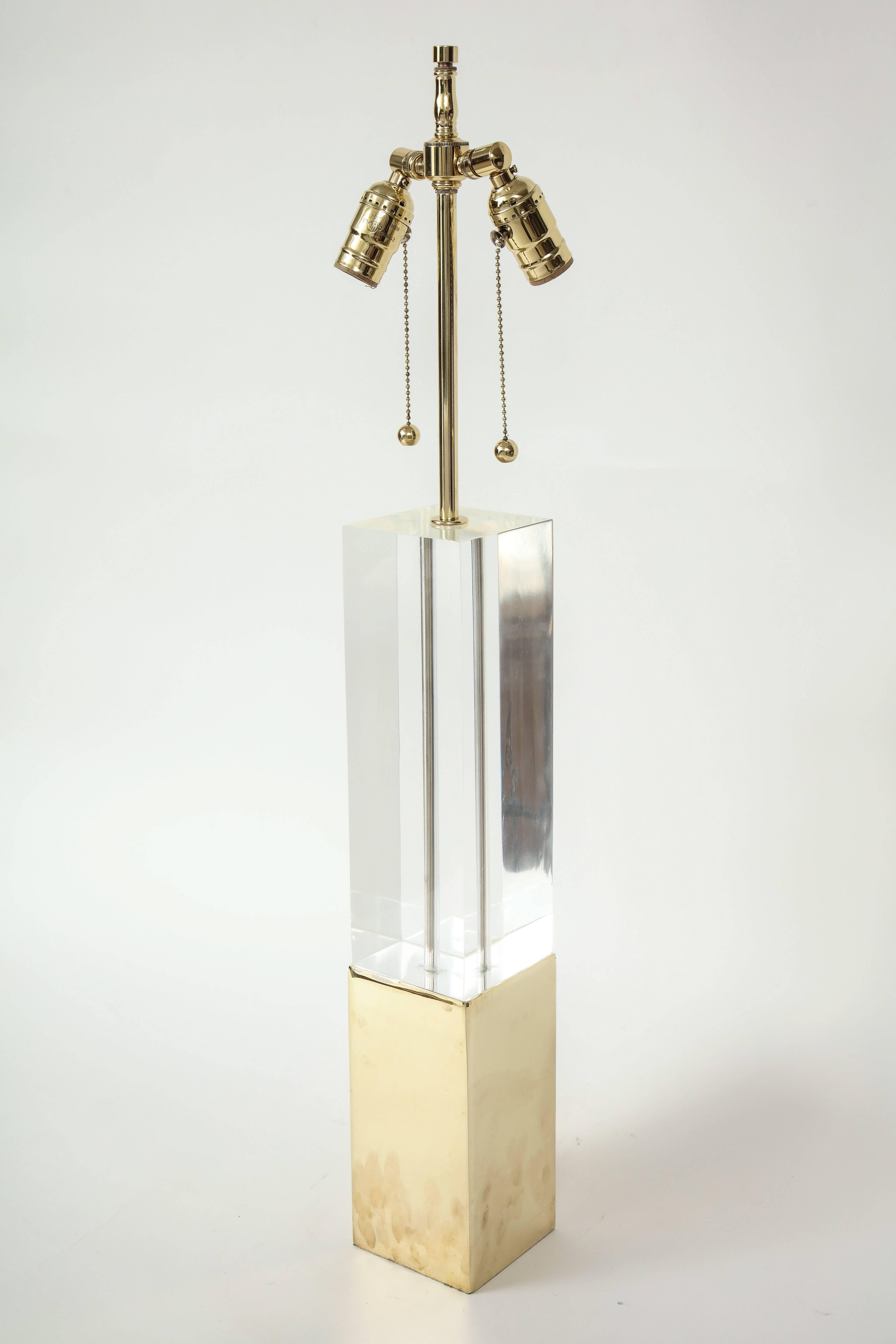 Striking pair of rectangular column lamps composed of solid Lucite columns resting on polished brass bases. Lamps feature brass double pull chain sockets. Rewired for use in the USA.