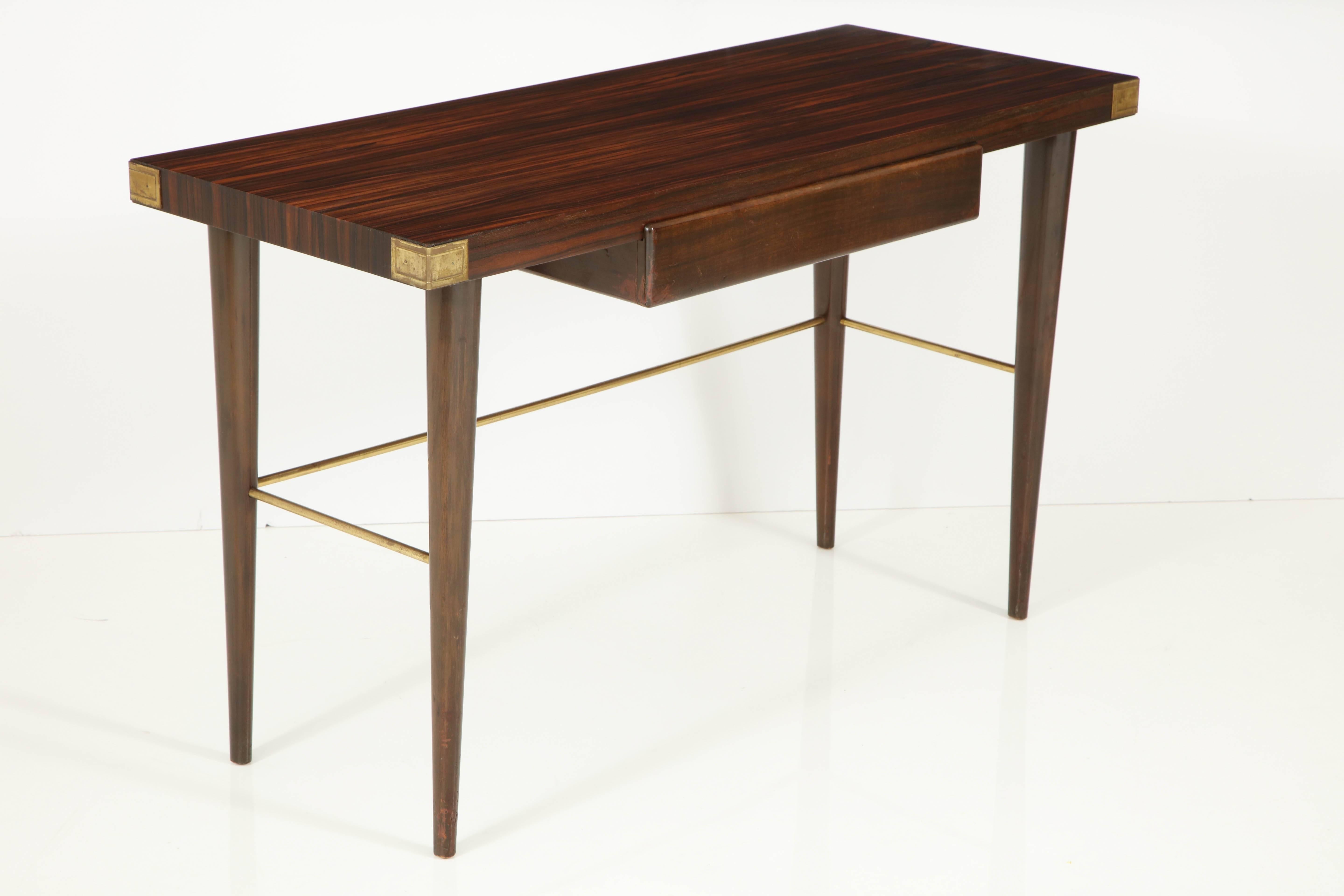 Sexy one-drawer desk with extravagantly grained Macassar ebony surface on mahogany legs with brass stretchers and corner decoration. Has a raised drawer front detail, mirrored-imaged on the desk backside, allowing for floating placement. Partial