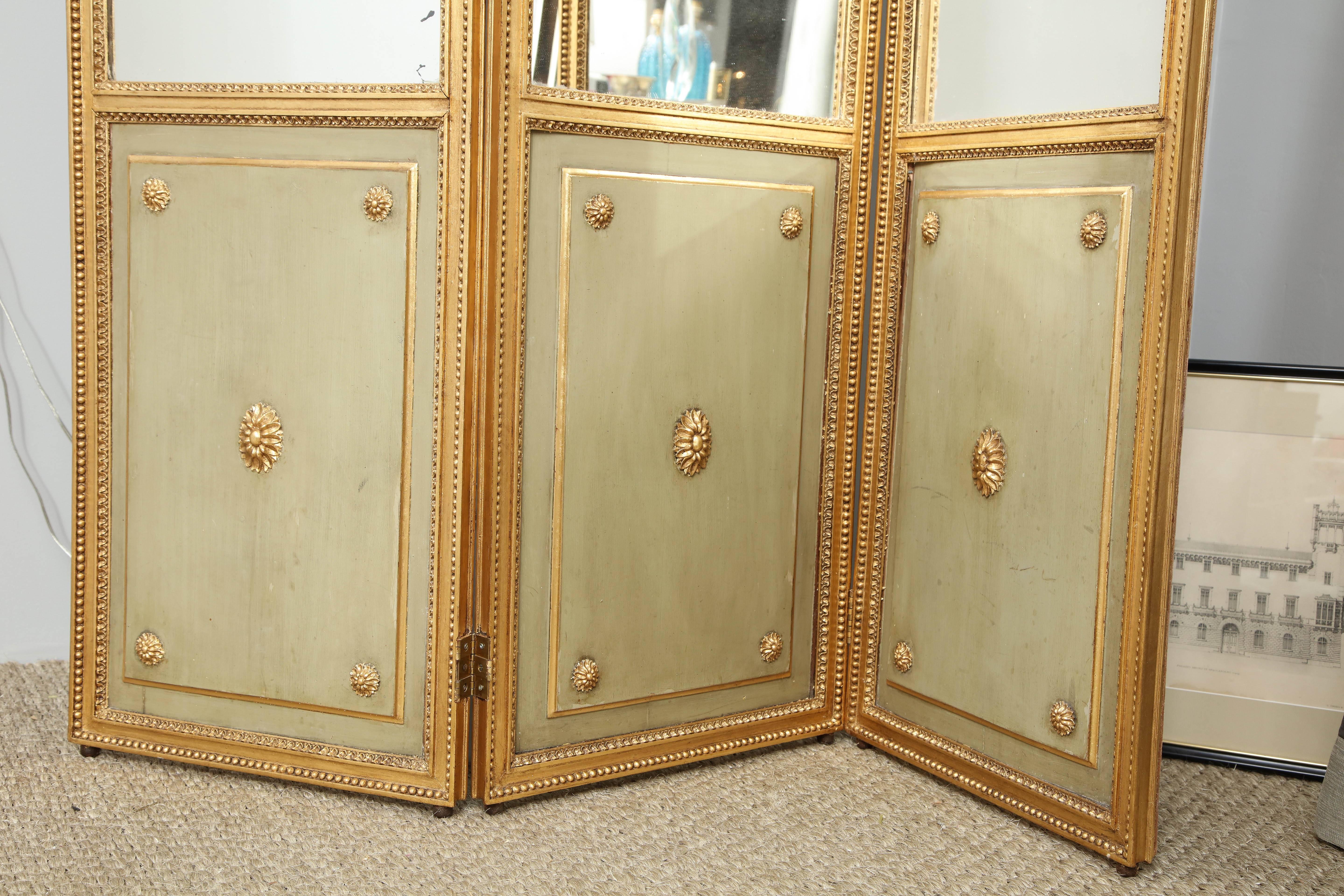 Screens can add some depth and architectural interest to a room, and this one is exceptionally good looking. This three-panel painted and parcel-gilt screen is surrounded by a beaded molded frame with lovely floral rosettes on each lower panel and