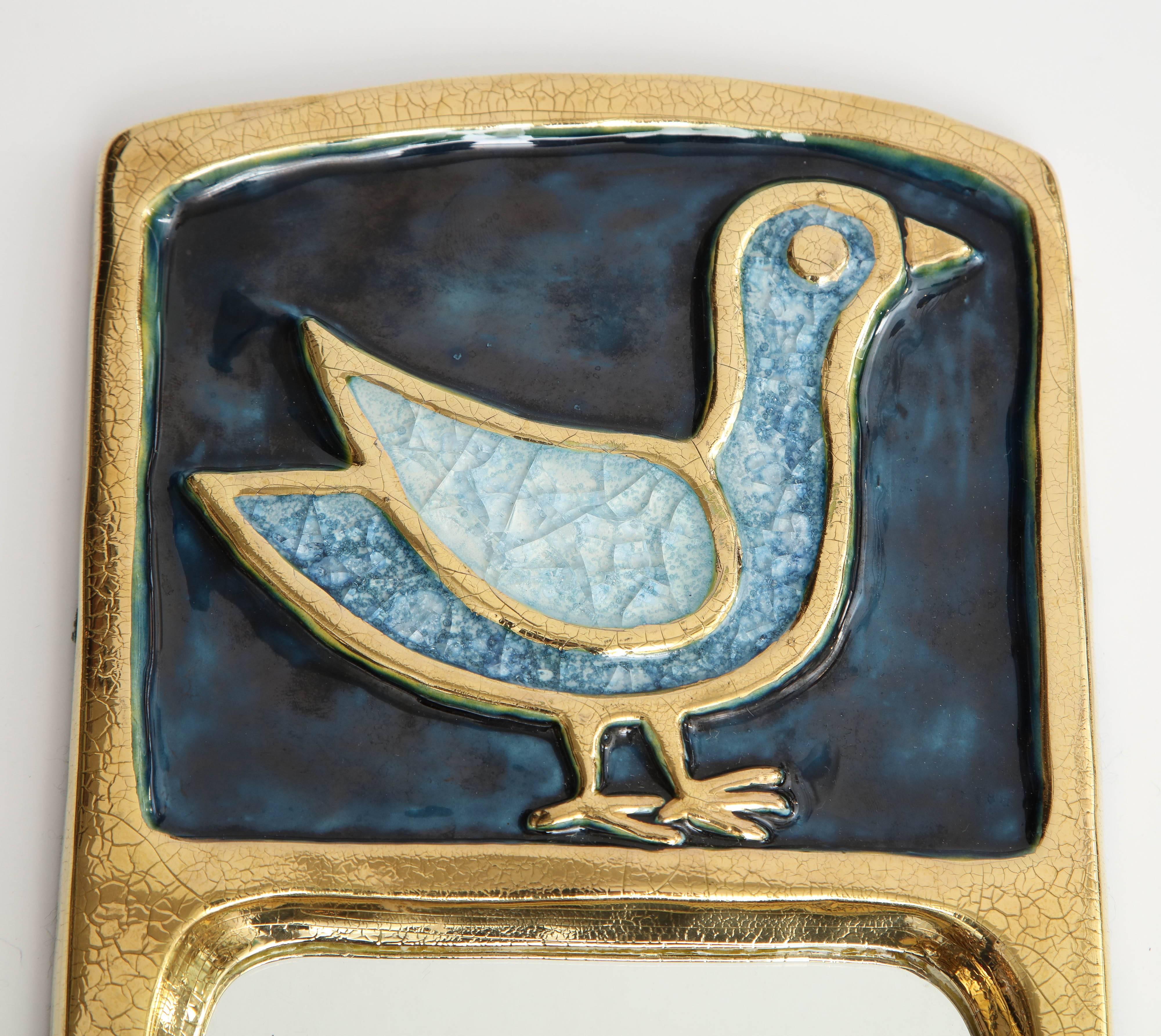 Inspired by Russian icons, artist Francois Lembo's creations are unique and beautiful.  This charming mirror features a frame in a gold crackled glaze with a bird in a blue stone in a stunning blue enamel ground color. A small piece with a lot of