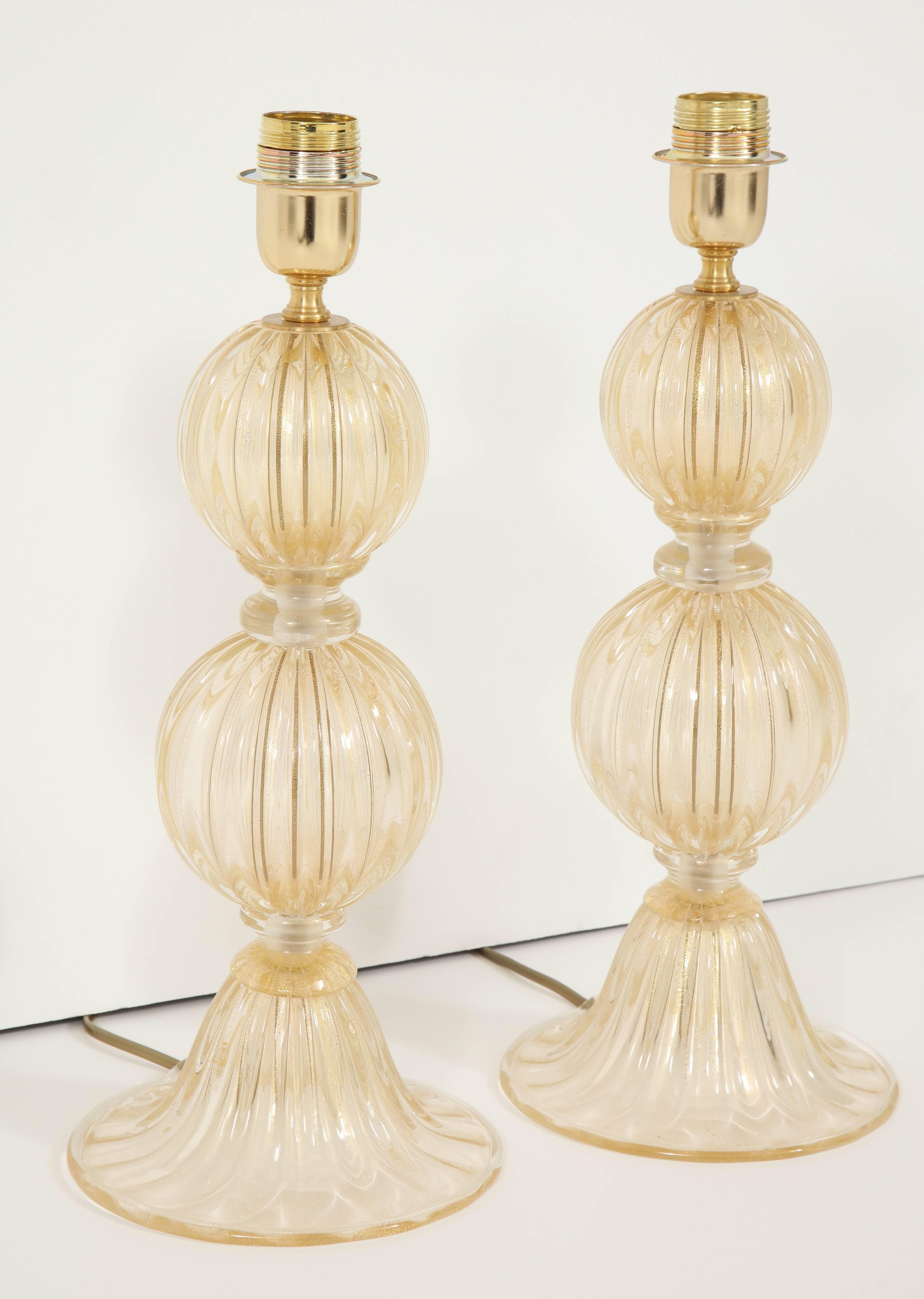 A stunning pair of Murano glass lamps composed of two sculpted globes separated by clear glass rings, decorated with gold leaf inclusions.