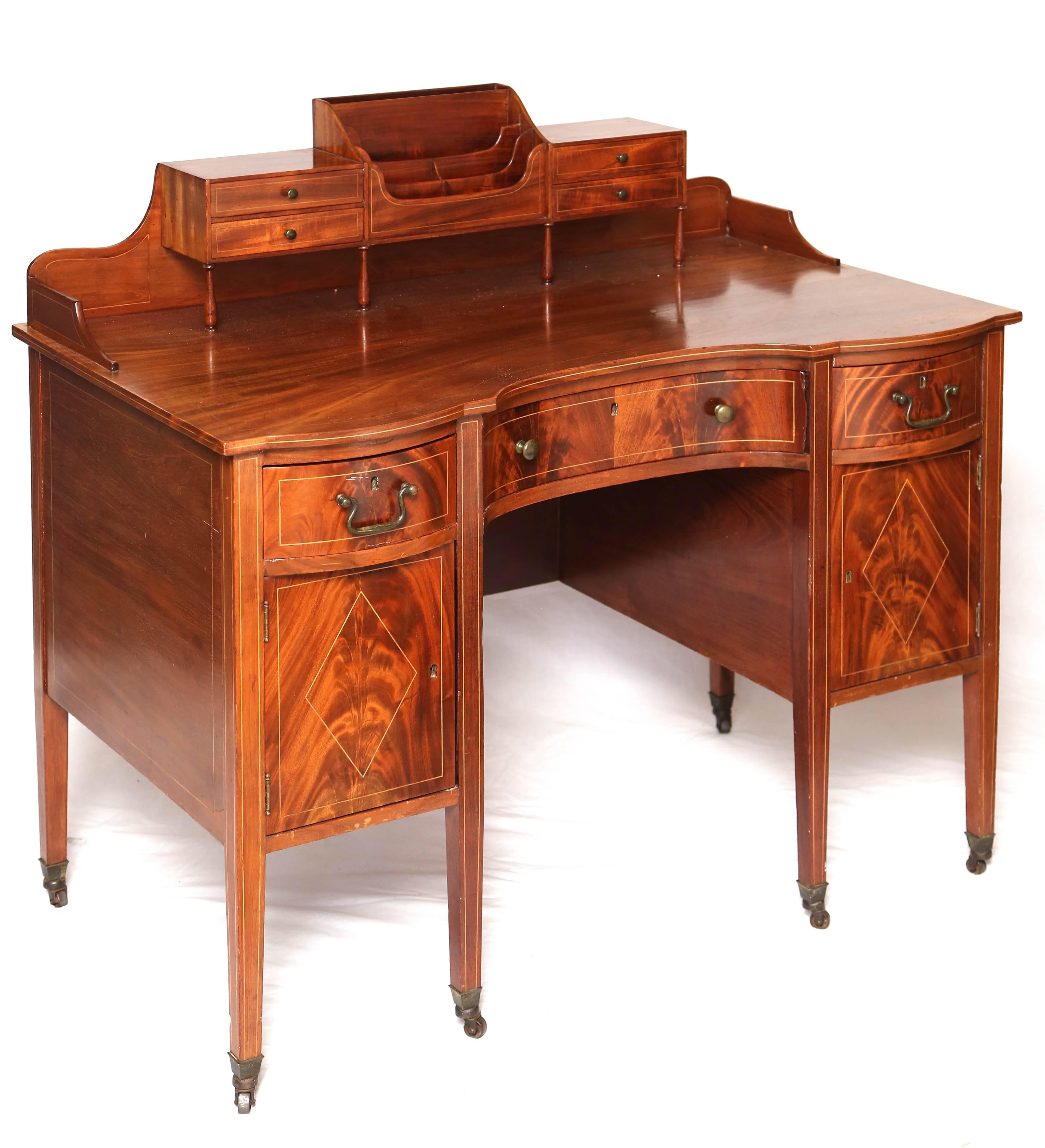 This is a very nice antique Mahogany writing desk, letter holder and drawers above three side by side drawers with cabinet doors, 40 H x 40" W x 25"D (at widest).
It has satinwood string inlay brass drop handles and also brass