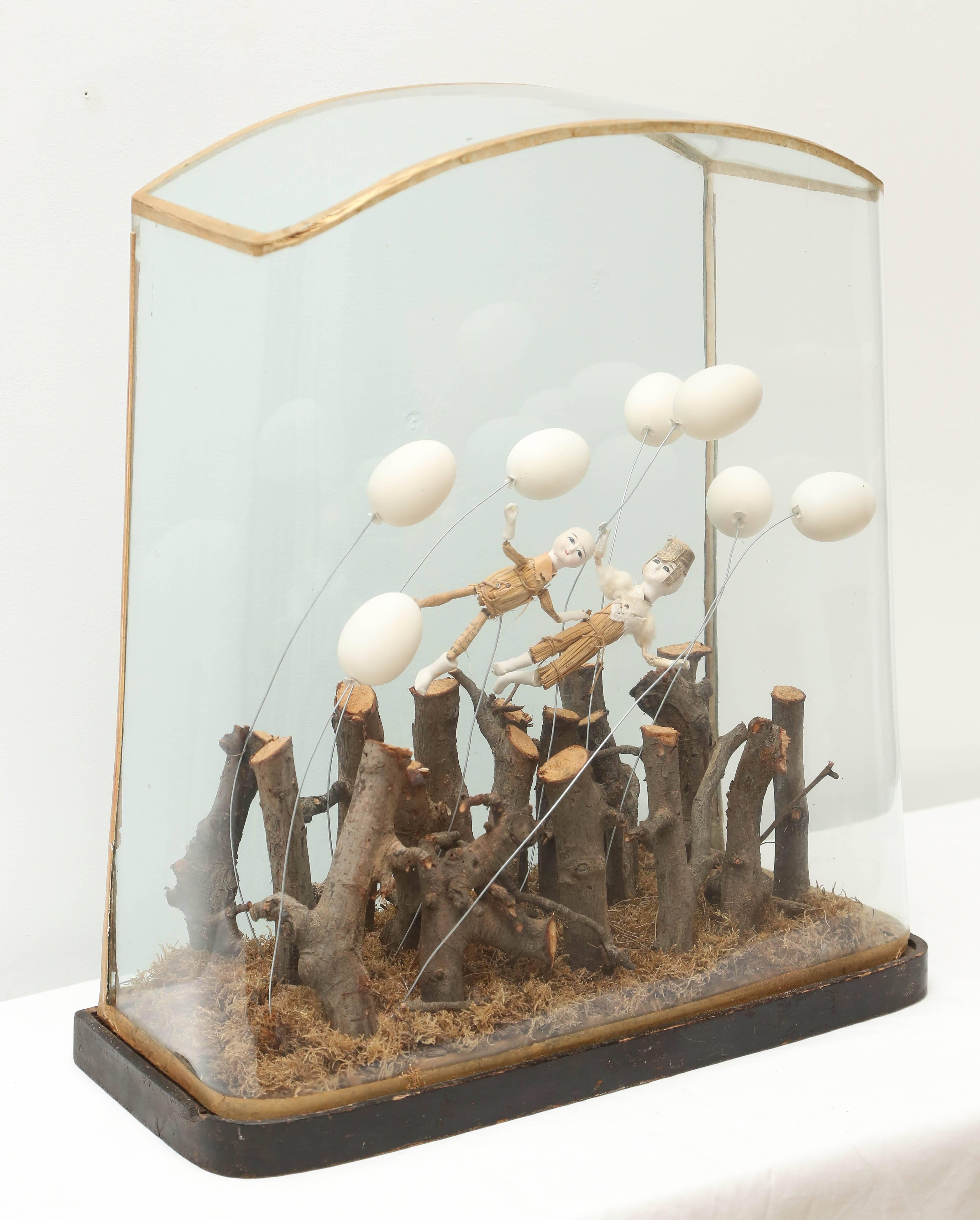 Whimsical fantasy of dolls drifting afloat with balloons of eggshell, encased in a glass display. The sculpture was made by a French artist and is unsigned.