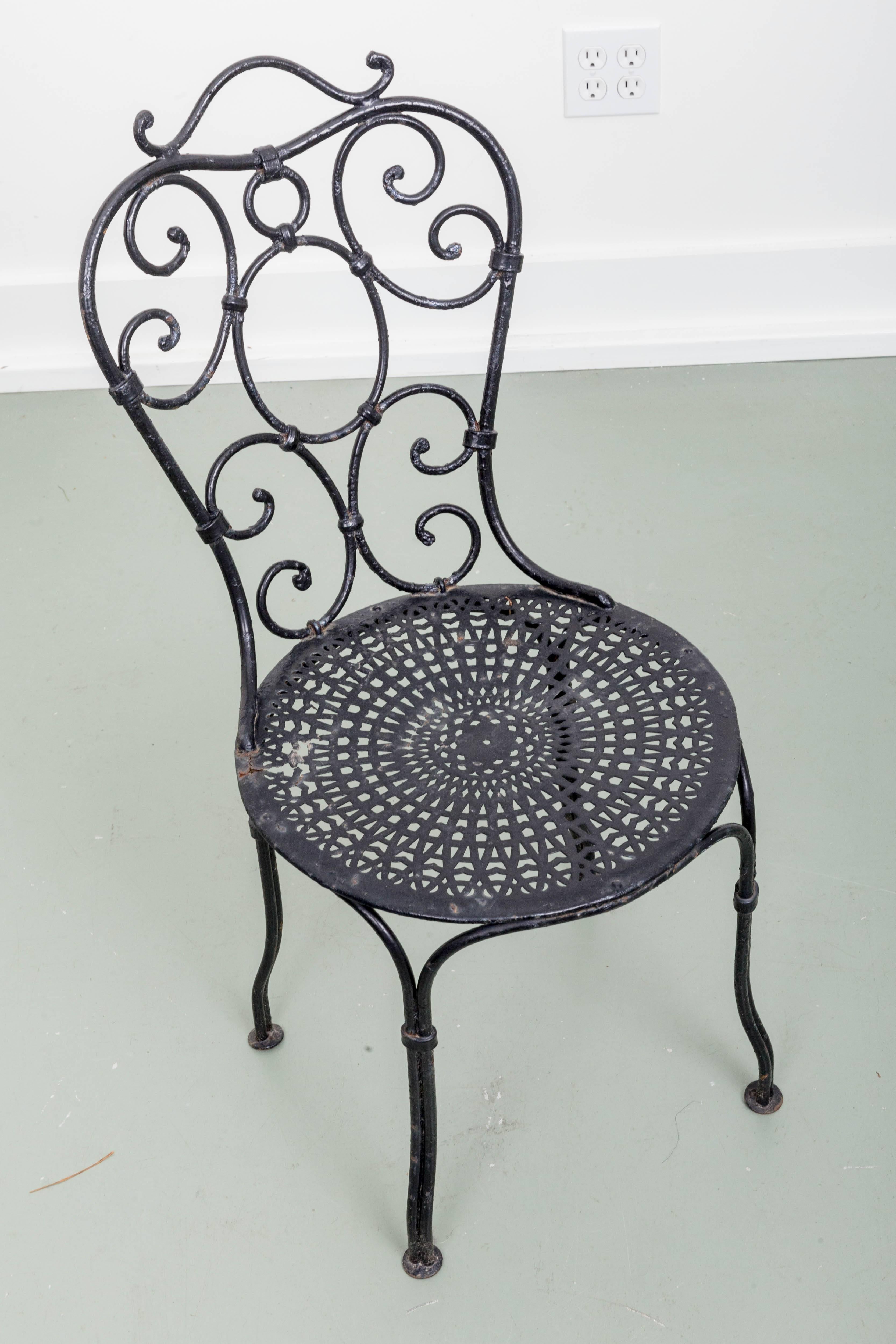 Pair of early French wrought iron garden chairs scroll backs with perfurated seats, from Paris.
